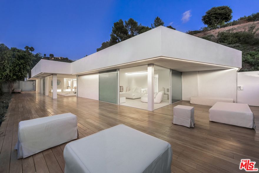 The Beverly Hills and California lifestyles come together in this newly completed first signature 1960s home re-imagined through the eyes of world-renowned architect Miguel Angel Aragones. Situated on a private perch with city and ocean views, the home is the perfect union of modern architecture with the natural setting creating the absolute finest indoor-outdoor living experience. From the moment of entrance, a spacious open floor plan, conversation living room, open dining area and kitchen all flow together for the ideal entertaining showplace. The 4 bedroom 4 bathroom home features the finest materials and pristine craftsmanship while boasting every cutting-edge technological amenity. Highlights of the home include a stunning master suite with a private shower garden, a lounge/media room, state-of-the-art kitchen and a kidney shaped pool. Quiet perfection, sophistication and elegance for a true quintessential Trousdale experience.