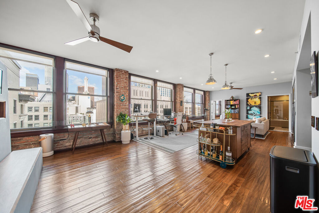Stunning, upgraded 2 BED, 2 BATH, 12th floor loft in the historic Rowan Building with spectacular city skyline views and treetops of Spring Street Park. The west-facing LIVE/WORK loft is situated just below the penthouse level, and features one of the largest floorplans. There is a bedroom and bath each on opposite ends of the unit. Take in natural light and gorgeous city views from ten oversized mahogany windows framed by beautifully restored exposed brick that span the entire length of the unit from room to room. The loft boasts over 10ft tall ceilings & hardwood floors throughout, and an open living area that's ideal for entertaining. There is a custom designer working electric fireplace and heater with temperature control and built-in storage and bench. The kitchen features Scavolini cabinetry, stainless steel appliances that include Bosch stovetop, dishwasher and Italian Fulgor oven, stainless steel fridge and microwave, and quartz countertops. Primary bedroom is separated by custom shelving, and features a massive closet & ensuite bath with quartz countertops. There is a second completely walled in regular bedroom with a door, and massive windows, wall-to-wall mirrored closet, and a guest bath just outside. Other features of this unique loft is a Bosch W/D in the unit, central heat/AC, Toto fixtures in bathrooms, ceiling fans, ambient window shades, and dimmable recessed lighting throughout. Amenities include 24/7 front desk security and reception desk that can accept and hold deliveries, outdoor deck that features hot and cold plunge pools, resident lounge, BBQs, outdoor dining/lounge area, extra basement storage options. Few short blocks to Grand Central Market, Metro, Arts District, The Broad, Walt Disney Concert Hall, MOCA, Little Tokyo, Whole Foods, Grand Park, tons of coffee shops & dining hot spots! Parking is available in the adjacent covered garage structure for an additional fee.