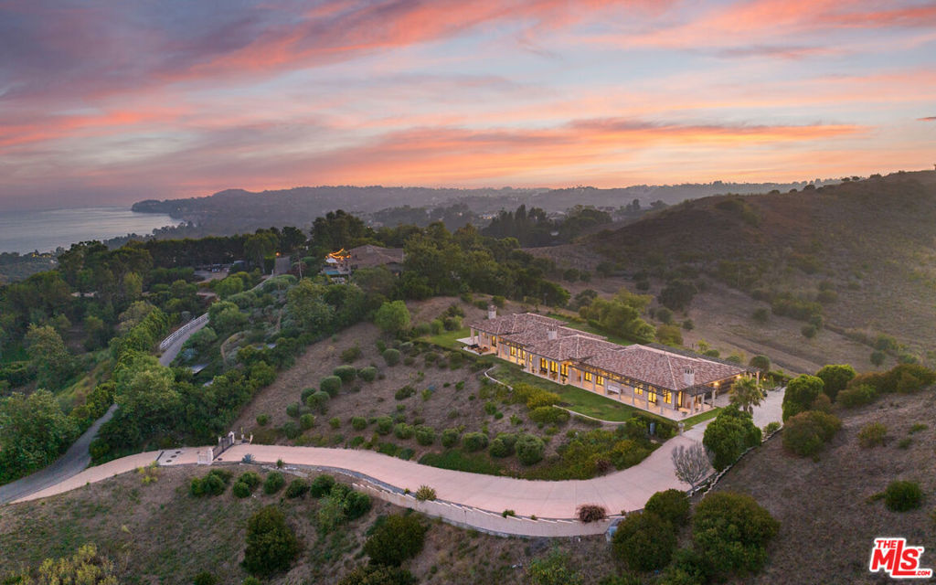 This luxurious coastal estate is a masterpiece of design, offering breathtaking ocean views from the moment you approach its expansive driveway. The grand entrance features a walkway lined with stately columns and stone tile floors, leading to a beautifully landscaped front yard. The front yard includes a spacious patio with a tranquil fountain, manicured lawns, and inviting benches, creating a serene atmosphere that sets the tone for the home.Upon entering through the covered front door, you are welcomed into an elegant foyer with intricate tile work and columns, guiding you toward the heart of the home. The living room, a large rectangular space, boasts stone tile floors, high wood-beamed ceilings, and a magnificent fireplace with a detailed mantle. Arched French doors open to the backyard, where sweeping ocean views enhance the seamless indoor-outdoor living experience. Adjacent to the living room, the dining area shares the same luxurious finishes and offers direct access to the backyard through French doors, making it perfect for both formal dinners and casual gatherings.The gourmet kitchen is a chef's dream, featuring top-of-the-line Thermador appliances, stone countertops, a large island with additional sink and storage, and two waterfall counter peninsulas for ample bar seating. The kitchen also includes a walk-in pantry and leads to a more formal dining room with a gas fireplace and French doors opening to the backyard and side yard. The estate features multiple bedrooms, each with wood floors, en-suite bathrooms, and either ocean or garden views. The master suite is a true retreat, offering expansive ocean views, high ceilings, a fireplace, and French doors leading to a covered deck. The master bath is equally luxurious, with stone tile floors, a large walk-in closet, a jetted tub, double sinks, and a steam shower.The outdoor spaces are designed for relaxation and entertainment, featuring a covered deck area, large grassy lawns with room for a pool, and a state-of-the-art sprinkler and security system. With two gated entrances and meticulously maintained landscaping, this property offers both luxury and privacy, making it a stunning sanctuary in a prime coastal setting.