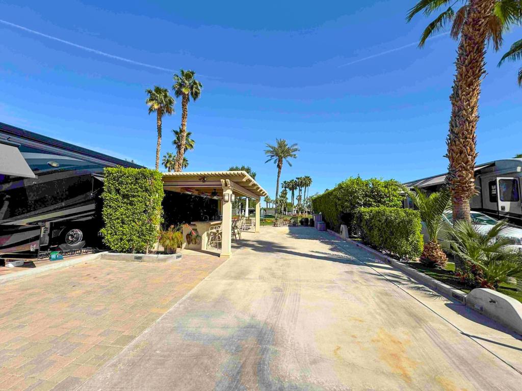 This centrally located luxury RV lot at Outdoor Resort Indio offers the perfect blend of convenience, privacy, and stunning views. Just steps from the clubhouse, pickleball, tennis, main pool, and gym, but far enough not to hear any noise. It's also a short walk to a satellite pool and laundry facility. Lot #225 is an east-facing premier golf course lot overlooking the 6th green, lake, and fountain, delivering a peaceful and picturesque setting from your paver patio. In the morning, enjoy a cup of coffee while watching beautiful sunrises and in the evening, enjoy mesmerizing moonrises accompanied by soothing sounds from the golf course fountain.Tall ficus hedges frame the space, offering natural privacy while still allowing open views of the golf course. The furnished outdoor living area is built for both relaxation and entertainment, featuring a covered pergola, electric drop-down shades, three heaters, and two fans for comfort. A medium-sized kitchen includes a full-size oven, brand-new rotisserie BBQ, dishwasher, and bar combo with generous counter space--ideal for gatherings and projects that require workspace. Lush landscaping and ample parking complete this exceptional retreat, designed for the discerning RV owner seeking comfort, style, and resort living at its best.‍‍Outdoor Resort Indio is a class A only RV resort in Indio, CA.