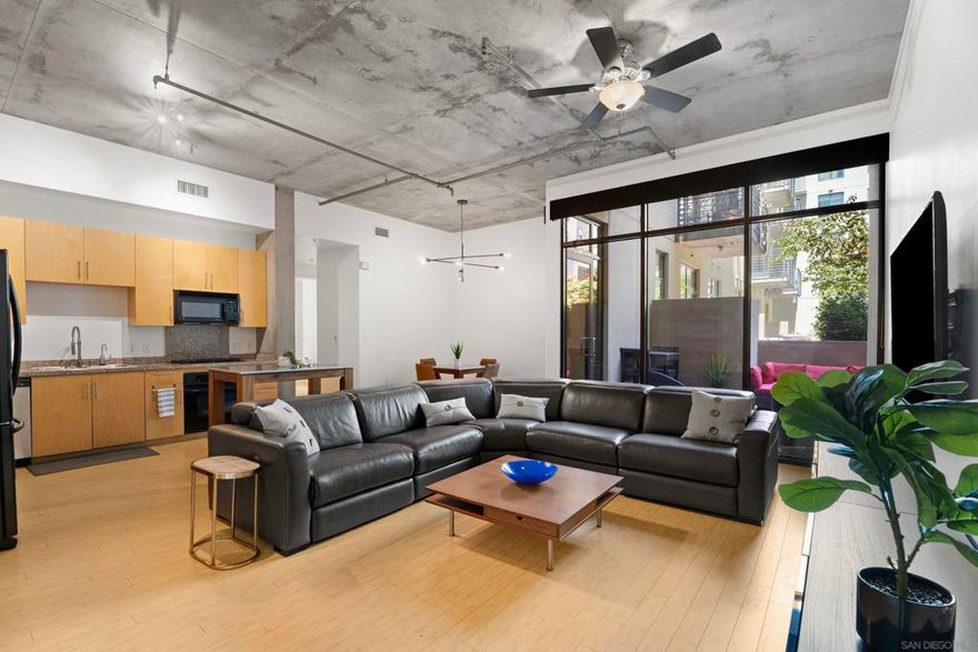 M2i Residence #210 offers ONE OF THE LARGEST COURTYARD PATIOS IN THE BUILDING! This stunning loft features expansive open space with soaring concrete ceilings, freshly painted crisp white walls, and two walk-in closets. You'll enjoy the convenience of in-unit laundry and central air conditioning. The sleek bamboo flooring and large windows create a sophisticated urban ambiance. Modern dining room lighting complements the space while the  private patio... ideal for outdoor dining, relaxation, and conversations begs you to appreciate the San Diego weather. An excellent underground parking space is protected by two large pillars. The community also includes a rooftop lounge and fitness center, enhancing this exceptional urban retreat. This is a truly rare find!