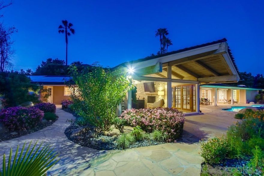 A gem in the hills! This single-story home exudes old Hollywood charm, showcasing stunning views and refreshing breezes. Upon entering you'll be greeted by a captivating stone wall/fireplace and panoramic hills through the living room's picture window. Embrace California living with a seamless indoor/outdoor flow from the kitchen and dining area onto the oversized covered patio and sparkling salt water pool.  The primary retreat offers a cozy fireplaces, French doors leading to pool and a spa-like bathroom for the ultimate retreat. Spend evenings entertaining and eating Al fresco with the backdrop of spectacular mountain views. Step down the stone stairs to the lower citrus grove, perfect for picking fresh fruit or simply enjoying the shade under the trees.  Boasting a fireproof roof and solar, this home offers both sustainability and cost savings. Included on the lot is a separate 1000 sq. ft. building, providing ample space for an RV, boat, gym, studio, or potential guest house. With limitless possibilities and just 20 min to the beach and downtown San Diego, this property is a rare find.
