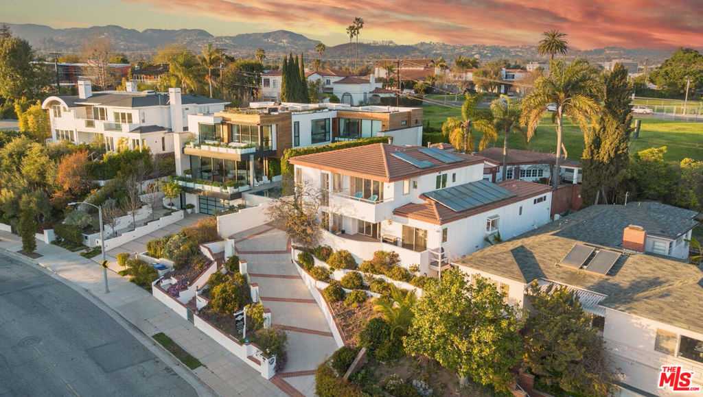 Perched atop Berkeley Street in Santa Monica, this exceptional 4-bedroom, 4.5-bathroom home offers panoramic views of the ocean, mountains, and city skyline. Designed to capture its stunning surroundings, the home features expansive windows and seamless indoor-outdoor flow, filling every space with natural light and breathtaking vistas. The open living areas lead to a tastefully designed kitchen that balances style and functionality. Outside, the private pool, spa and yard provide a perfect setting for relaxation and entertaining while enjoying sweeping views. The luxurious primary suite boasts a spa-like bathroom with a freestanding tub, rain shower, dual walk-in closets, and a cosmetic vanity table. A private balcony offers stunning views of Santa Monica, ideal for morning coffee or sunsets. Each of the four bedrooms includes an en-suite bathroom, ensuring privacy and comfort. A flexible fifth room on the main level is perfect for an office, den, gym or guest room. Additional features include an elevator, dumbwaiter, and a spacious two-car garage with ample storage. Conveniently located near the Brentwood Country Mart, Brentwood Country Club, and Montana Avenue, this home is also just minutes from the Santa Monica Pier and beaches. With its prime location, top-rated schools, and breathtaking views, it offers the perfect blend of luxury and convenience.