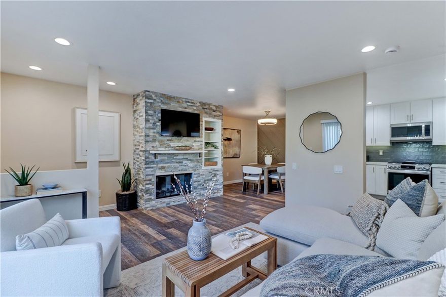 Experience elevated living in this beautifully reimagined ground-floor residence, thoughtfully upgraded to feel more like a sophisticated townhouse with its rare and convenient direct street access. The open-concept layout is designed to impress, featuring a striking stacked-stone fireplace with shelf, mounted flat-screen television, custom built-ins, recessed lighting, smooth ceilings, and luxury vinyl plank flooring that flows seamlessly throughout the home. The dining room showcases a stunning board-and-batten feature wall complemented by a sleek, modern invisible ceiling fan. The chef-inspired kitchen has been meticulously updated with soft-close shaker cabinetry, elegant quartz countertops, subway tile backsplash, under-cabinet task lighting, recessed lighting, a stainless farmhouse sink, and LG stainless-steel appliances. A generous patio offers an ideal setting for outdoor dining or afternoon relaxation and includes a spacious storage shed for added convenience. The serene primary suite features a large walk-in closet and a spa-caliber ensuite bath complete with a double quartz vanity, refined hardware, LED mirrors, and sophisticated designer lighting. The second bedroom includes a mirrored wardrobe, recessed lighting, and direct access to the balcony. The beautifully updated guest bathroom impresses with its quartz-topped vanity, LED mirror, modern lighting, and custom-tiled tub surround. Additional highlights include newer dual-pane windows and sliders, central air and heat, an LG washer and dryer, NEST thermostat, linen storage, and a secure covered parking space. East Park Villas provides an array of amenities including a pool, clubhouse, outdoor showers, elevators, and HOA dues that cover hot and cold water, trash, and sewer. The community welcomes two pets under 40 pounds. Centrally located near freeways, dining, shopping, beaches, and fitness options, this exceptional residence blends elegance, comfort, and convenience—all just moments from the vibrant Long Beach Traffic Circle. Best of all, enjoy effortless parking right outside your front door and skip the hassle of stairs and elevators, especially when unloading groceries. A home of this caliber, with such thoughtful and recent upgrades, is a rare opportunity. Don’t miss it. VA approved community!