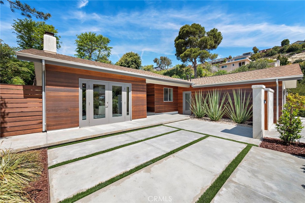Incredible opportunity for a Single Level home in Laguna Beach that is completely remodeled with sophisticated modern amenities and impeccable upkeep. Situated on a private lot of approximately over 9,300sf with wonderful indoor, outdoor access and landscape views through all rooms of the home. A fusion of quality sourced materials were utilized throughout. Starting with the solid Redwood outdoor privacy entry gate, which leads to a large front flat patio and custom front door. The open living, dining and kitchen spaces flow seamlessly for entertaining and every day living. Crystal gas burning fireplaces and oversized glass paned French doors adorn the living and formal dining spaces. The Chef’s kitchen comes complete with Thermador Professional six burner range, double oven and built-in refrigerator/freezer. Quartz countertops and bar seating with modern glass pendant bar lighting. Oversized stainless steel sink and fixtures, Porcelain linear tiled backsplash. Custom kitchen cabinetry with soft close drawers, doors and pantry pull outs. The separate bedroom wing consists of a primary suite and two additional bedrooms with bath. The primary bedroom features a high ceiling with skylight, reclaimed wood accent wall and French doors that look out to a lush side garden. The primary en suite bathroom has oversized shower, separate tub and walk-in closet. Both bathrooms have dual Kraus vanities, Porcelain tiled showers and flooring. The home also has French Oak engineered hardwood flooring and Limestone tiling throughout the main rooms.  Plentiful natural light is enjoyed throughout this floor plan, enhanced by dual paned windows, French doors and skylight tubes. Systems of central heat, air, ducting, tankless water heater, water softener have been updated. The attached two car garage allows easy access from parking to home interior with minimal entrance steps. The added convenience of an office nook creates a getaway home work space. Exterior enhancements include stucco and Redwood sided building exterior. Spacious front, side and rear patio areas. Redwood decking, crystal gas firepit and gas plumbed for barbecue connectivity. The private back slope and front planters have been updated with native, colorful plantings and landscape lighting. Conveniently located on the loop that is Bern Drive in lower Top of the World. Close to award winning LBUSD schools, Alta Laguna Park and just minutes down Park Avenue the heart of downtown.