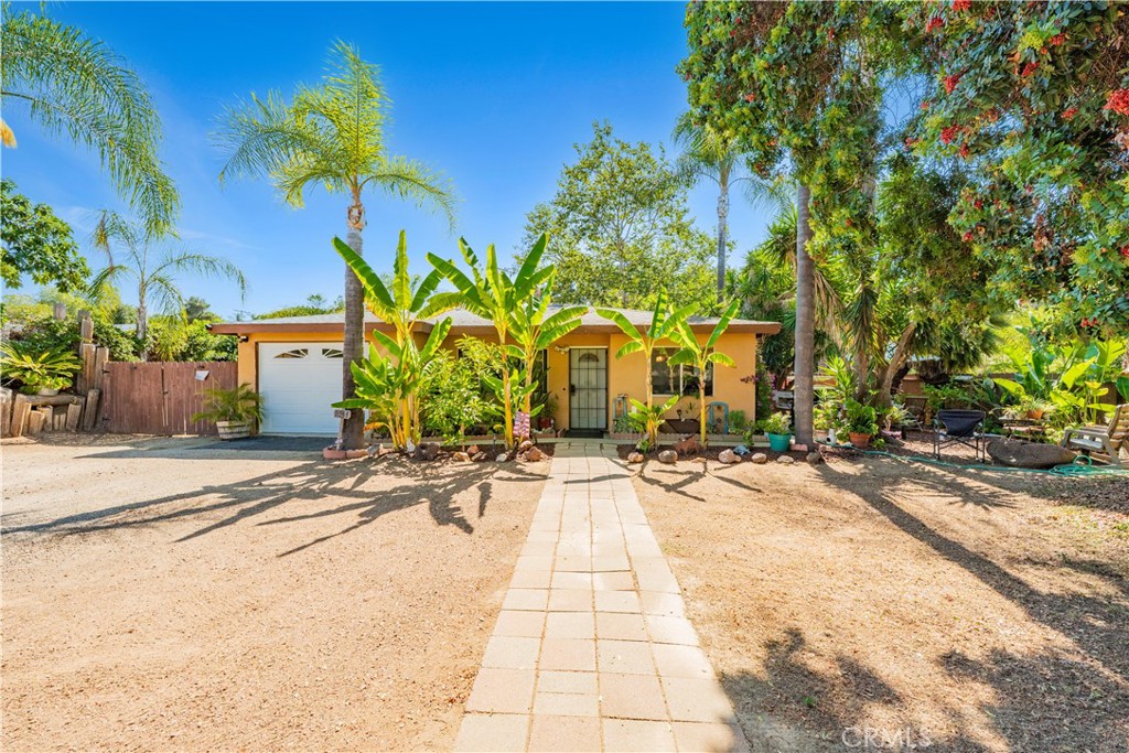 Welcome to 2048 Pomegranate Lane, a coastal-inspired slice of paradise nestled in the heart of Fallbrook, where California charm meets laid-back living. This single-story home offers 3 bedrooms, 1.5 baths, and a spacious 11,326 sq ft lot filled with natural beauty and everyday serenity. From the moment you arrive, the curb appeal is undeniable—framed by mature palm trees, vibrant succulents, and a colorful variety of fruiting trees including orange, lemon, avocado, champagne grapes, and more. This is the kind of home where mornings begin in the zen garden, afternoons are spent tending to fresh veggies, and evenings are made for al fresco dining beneath the stars. Inside, the home offers 1,172 sq ft of cozy, sun-filled living space anchored by a charming wood-burning fireplace and French doors that open directly to the backyard from the primary bedroom. All appliances are included, and recent improvements like a newer water heater make daily life easy and comfortable. The side patio—lined with beautiful pavers and shaded by an avocado tree—is perfect for quiet morning coffee or weekend entertaining. A one-car garage, multiple exterior plumbing access points, and public utilities including city water and sewer provide convenience, while propane and a shed with electricity add flexibility for future use. The property is low-maintenance and thoughtfully designed with mulch and woodchips throughout, offering beauty without the upkeep. The fully fenced yard includes space for motorhome or RV parking and invites you to relax and breathe. You’ll love the friendly neighbors, peaceful vibe, and easy access to the best of Fallbrook—just moments from the 76 freeway, Downtown Fallbrook, renowned golf courses, and local wineries. Only 30 minutes to the beach, this home blends countryside calm with coastal proximity. 2048 Pomegranate Lane offers the best of Southern California living—a place to plant roots, grow memories, and enjoy life’s simple pleasures. Homes like this are rare, and the lifestyle it offers is even rarer. Don’t miss your chance to make it yours.