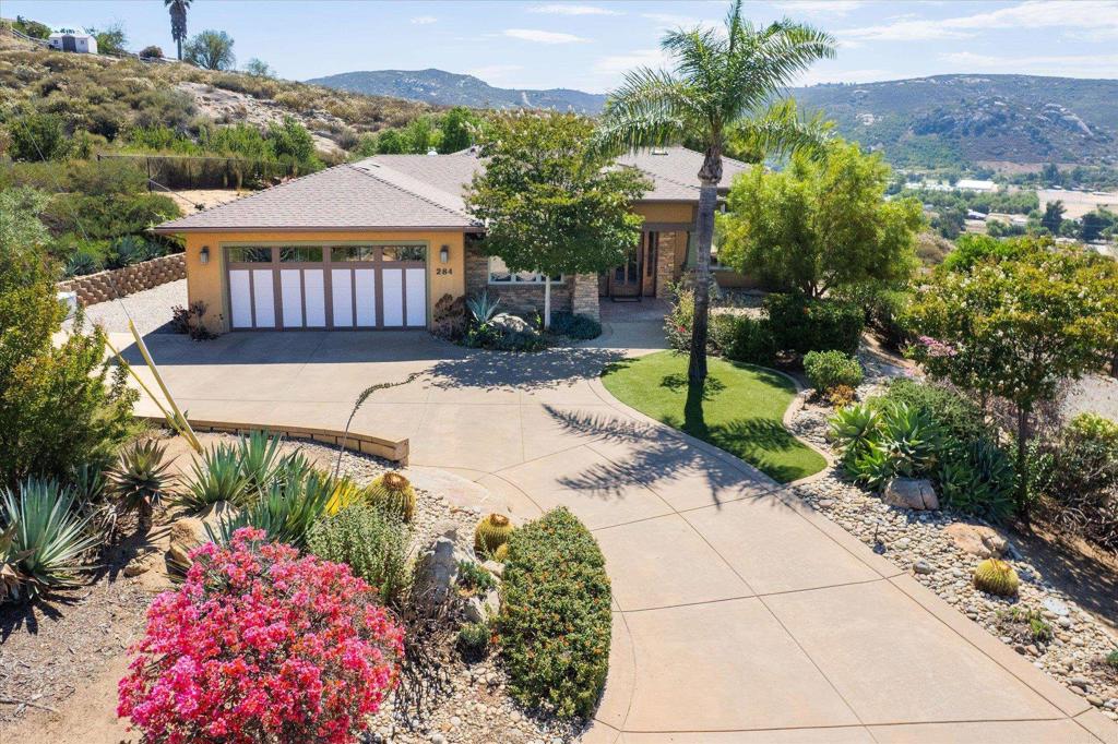 Wow, a Contemporary Craftsman Retreat with Sweeping 270° Views! Perched high on a hill in Ramona, California, this stunning 3-bedroom, 2-bathroom 2,496 sq ft contemporary craftsman-style home was thoughtfully designed by renowned architect Carole Wylie to capture breathtaking 270-degree panoramic views of the surrounding valley and mountains. Step inside to discover custom cabinetry throughout, elegant travertine flooring, and a spacious open-concept chef’s kitchen with KitchenAid stainless steel appliances which includes a double convection ovens, a 5-burner stove, built-in fridge, and water filtration , and an easy flow into the great room. With 12-foot ceilings, exposed wood beams, travertine floors and a beautiful stone fireplace, the living area is both grand and inviting. The adjacent formal dining room is enhanced with built-in china cabinets and expansive windows that frame the spectacular scenery. Natural light floods the home through large picture windows and multiple sliding glass doors, leading to a series of patios perfect for outdoor entertaining or peaceful moments of solitude. The primary suite is a true retreat, complete with its own fireplace, a spa-inspired bathroom with a freestanding soaking tub, large walk-in shower, and a private patio entrance leading to a hot tub—the perfect place to unwind under the stars. Additional features include a Paid solar system with a 10kW backup generator with automatic transfer switch and an electric car charger. The three-car tandem garage has a shop area with built-in cabinetry for extra storage and epoxy flooring. Outside is just as magical with its beautiful landscaped yard including citrus trees and garden boxes and plenty of room to roam and relax. The backyard is fully fenced including snake fencing! There is also RV parking with hookups, a 10,000 gallon holding tank and a cleared pad which is ready for you to add an ADU, Barn, Shop or whatever your lifestyle calls for. This home is more than just a place to live—it's a lifestyle. If you're searching for serenity, space, and unforgettable views, this is the one. Come experience the magic of this one-of-a-kind home in person—you won’t want to leave!