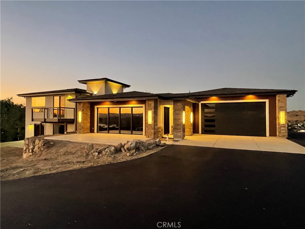 This newly built home on over a 1/2 acre, perched high atop of the coveted subdivision of Lakeside Village in Heritage Ranch. 15 minutes from Paso Robles, This property has 360° sweeping views of the Santa Lucia Mountain range, and Lake Nacimiento. There is a large flat turnaround area with ample parking for all your vehicles, including an RV site with a sewer & electrical hook up.
Stucco & Custom aluminum horizontal siding, Real stone walls cut from a quarry in Texas. The lakeview patio has Italian tile that flows right into the living area through the 16-foot-wide retractable glass door. The garage is 30’ x 30’ with a 10’ foot tall and 18’ foot wide Insulated door. There is an inside laundry room located in the garage. Once you walk through the steel custom double doors you will notice the Reclaimed Beam ceiling originating from a barn, built by the Amish in 1870. The wall facing the lake with the 16' retractable door is adorned with quarried Stone of a different style to look old in Spanish Hacienda. GE Appliances, custom cabinets, and a knotty Alder Island. Cabinets have quartz countertops as do all the windowsills. Off the kitchen is a large pantry with ample food storage shelving and a coat rack. Adjacent to that is a powder room with Barn Wood wains coating. This home is a split level, minimizing elevation changes & taking advantage of all the views. Six steps up to the gracious master bedroom, which is approximately 24 x 22 overlooking Lake Nacimiento to the south as well as the coastal Hills in the distance, the en suite boast a Jetted bathtub 6’ foot in length to fit most any adult, as well as a walk-in shower with Subway tile, besides the vanity with dual sinks there is a custom make up station and a bidet for all your personal hygiene needs. The master bedroom closet is approximately 16 x 12 and can fit everyone’s clothing and whatever you need to store. On the lower level also only six steps from main living area is a great room for your billiards table TV foosball in any entertaining purposes you might desire. This room also boast's great views of the lake. There are an additional two bedrooms, and a full three-quarter bath located on this level. The built-in shower has Italian tile, and the vanity has a quartz countertop. All the doors in this home are knotty Alder and stained a warm honey color. There is ample level space to make any future improvements such as pool, or other ideas.
