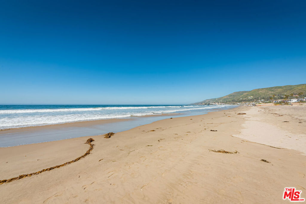 This gorgeous Point Dume gated compound with Little Dume/Riviera III beach key plus a private, gated path that leads to the beach, sits on more than 1.5 acres. Newly renovated, elegant, and ultra-private, this beautiful home is ideal for indoor-outdoor living and entertaining. At the heart of the house is an enormous great room with wood floors, high, wood-beamed ceilings, and a beautiful piano. This handsome room includes a living area, with gas/wood fireplace and built-in bookshelves, a dining area, and a gracious country kitchen with high-end appliances, large island, wood-burning pizza oven, dry-bar with ice machine, and butler's pantry with an additional pantry room. A wall of French doors open onto a huge flagstone patio. Off the great room, a family room doubles as a projection room, with blackout curtains over doors opening to the pool/spa terrace. A hallway with a window seat leads to the bedroom wing, where four bedrooms include two that share a bath, another en-suite, and the lovely owner's hideaway, which has a sitting area with a fireplace, a window seat looking out to the pool, double large closets, generous bookshelves, an office area, and a luxurious bathroom with freestanding tub, double-headed shower, double vanity, huge walk-in closet, and a wall of ocean-view windows. French doors open to a patio and lawn. Upstairs is an additional sleeping area with sitting area, fireplace, bathroom, and private deck with ocean views. The impressive grounds invite relaxation and grand hospitality. Features include a waterfall grotto pool/spa with a slide, sauna, outdoor kitchen and barbecue, large covered dining/sitting area with outdoor heaters and fireplace, flagstone patio with a fountain, sitting area with a fire pit, and extensive lawns. The yard is beautifully landscaped with fruit and other trees, and paths lead through the terraced plantings, including a vegetable garden. The outside space can also provide the opportunity to lodge chickens. There are two guest accommodations. The guest house is complete with sitting area with kitchenette, bedroom with fireplace, bathroom, walk-in closet, and a door to the patio and pool. A separate guest suite above the garage includes a great room with kitchenette, bedroom, bathroom, and French doors to a huge dining/sitting deck with ocean views. The property has garage parking for six cars and ample guest parking. Right along this exclusive beach path sits the surfboard shack, strategically positioned for maximum convenience. This is an exceptional home of rare size and quality created for the quintessential Southern California lifestyle. Yearly beach key fee.