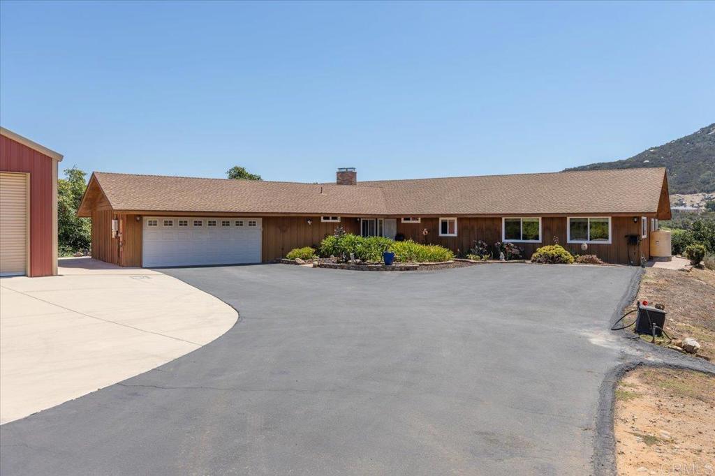 3.48 private acres, a massive RV barn/workshop, and a spacious single-level custom home— close-in but very secluded! This one-of-a-kind property is perfect for a home-based business, hobbyist, or anyone craving space, privacy, and endless possibilities including a 40' x 50' RV barn/workshop with two-story ceilings, an oversized 3-car garage, and a 2,629 sq. ft. beautifully maintained home. The 40' x 50' metal barn offers abundant storage and extensive parking, ideal for large equipment, RVs, or recreational vehicles or car collection. The gently sloping 3½ acres are ready for your vision — start a cash crop, create gardens, keep animals (as zoning permits), or design your dream outdoor retreat. Inside, pride of ownership shines. The spacious great room boasts vaulted ceilings, a masonry fireplace, and a large, custom wet bar — an entertainer’s dream. The large kitchen features beautiful birchwood shaker style cabinetry, generous counter space, a center island with electric cooktop. The primary suite offers a private dressing area, separate toilet room, and an oversized walk-in closet. All bedrooms are generously sized, and three bathrooms — including one in the garage for added convenience. The oversized garage accommodates up to three cars plus additional storage. Outdoor living is equally inviting with a covered back porch, deck with patio cover, above-ground spa, and a charming playhouse for kids or grandkids. With no close neighbors, you’ll enjoy peace and privacy — yet quick access to Gopher Canyon Road puts Vista, Bonsall, and Escondido within easy reach. Whether you’re looking to run a business, cultivate the land, or simply enjoy a serene retreat, this versatile property delivers the space, amenities, and setting to make it happen!