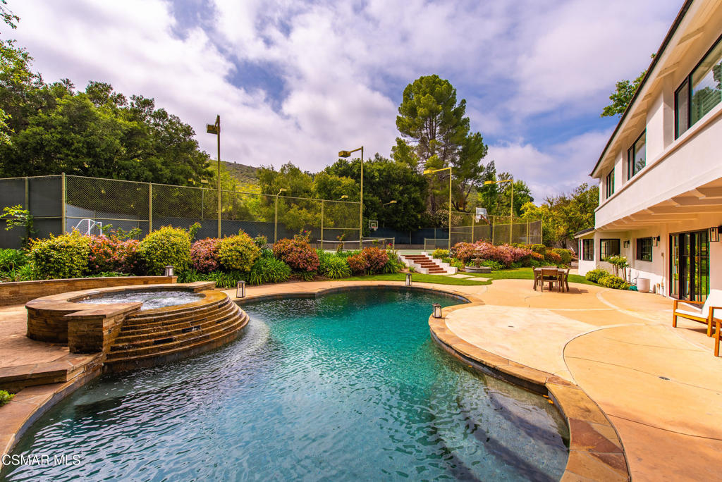 Tucked at the end of a quiet cul-de-sac in the prestigious North Ranch community of Westlake Village, this exceptional and remodeled 4-bedroom, 3.5-bathroom residence with pool and tennis court blends timeless sophistication with luxurious indoor-outdoor living. Fully remodeled exterior with brand-new Santa Barbara stucco, custom windows and doors, and a new roof add to the home's elevated curb appeal and lasting quality. From the moment you enter, soaring ceilings and an abundance of natural light set the tone for the home's open and inviting layout. The formal living room flows effortlessly into a refined dining area, while the updated kitchen impresses with high-end appliances, custom cabinetry, stone countertops, and a functional layout that opens to the spacious family room--perfect for relaxed gatherings and entertaining. The first floor is thoughtfully arranged with a private bedroom and full bathroom ideal for guests or multigenerational living, along with a charming office nook, a powder room, a full laundry room with storage, and direct garage access.Step outside into a backyard that rivals luxury resorts--designed for both grand entertaining and serene relaxation. This private oasis features a sparkling pool and spa, a full-size private tennis court, expansive patios for lounging or dining al fresco, and lush landscaping that creates a peaceful, secluded atmosphere. Newer back doors and windows seamlessly connect the indoor and outdoor spaces, inviting you to enjoy California living at its finest.Upstairs, the spacious primary suite offers a quiet retreat, complete with a private balcony, walk-in closet, and a spa-like bathroom with granite countertops, dual vanities, oversized shower, jacuzzi tub, and a convenient laundry chute. Two additional bedrooms have a beautifully updated hall bathroom with dual sinks and a large glass-enclosed shower. A generous three-car garage completes this rare offering in one of Westlake Village's most coveted neighborhoods. With luxurious amenities, flexible living spaces, and a spectacular entertainer's backyard, this North Ranch home offers the ultimate in comfort, privacy, and California lifestyle.