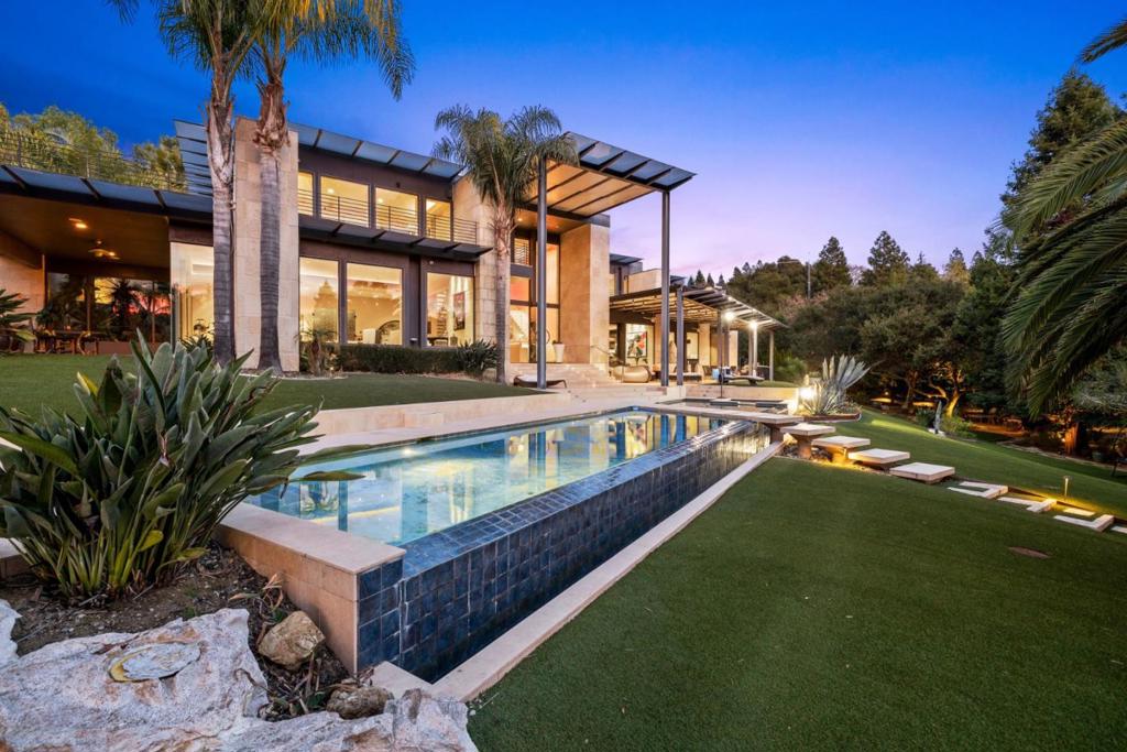 Built from 2008 - 2013 with exceptional quality construction and expanded in 2022 with an addition of the attached ADU with a private entrance. The main house offers eight bedrooms (including the guest unit), 11 bathrooms (including two half baths), a formal dining room, a large entertaining area with a wet bar, gym, home theatre with 16 leather recliners, wine cellar, an elevator, heated floors, 5 car garage, and 2 EV charges. The attached guest unit/ADU includes a private entrance with its exterior staircase, 2 bedrooms and 1.5 baths, a living room, a full kitchen, and a balcony with a stunning view. The property includes a rooftop solar system with storage batteries, generator/enclosure, sports court, limestone terraces and balconies, built-in BBQ, infinite swimming pool, and an evergreen garden with over 20 palm trees, waterfalls, and sculptures creating a sense of a private resort.