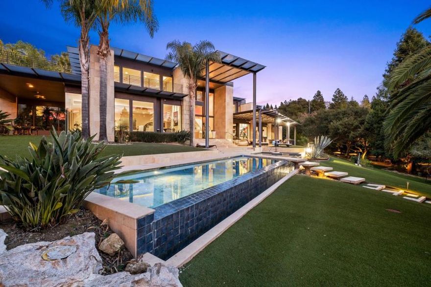Built from 2008 - 2013 with exceptional quality construction and expanded in 2022 with an addition of the attached ADU with a private entrance.  The main house offers eight bedrooms (including the guest unit), 11 bathrooms (including two half baths), a formal dining room, a large entertaining area with a wet bar, gym, home theatre with 16 leather recliners, wine cellar, an elevator, heated floors, 5 car garage, and 2 EV charges. The attached guest unit/ADU includes a private entrance with its exterior staircase, 2 bedrooms and 1.5 baths, a living room, a full kitchen, and a balcony with a stunning view. The property includes a rooftop solar system with storage batteries, generator/enclosure, sports court, limestone terraces and balconies, built-in BBQ, infinite swimming pool, and an evergreen garden with over 20 palm trees, waterfalls, and sculptures creating a sense of a private resort.