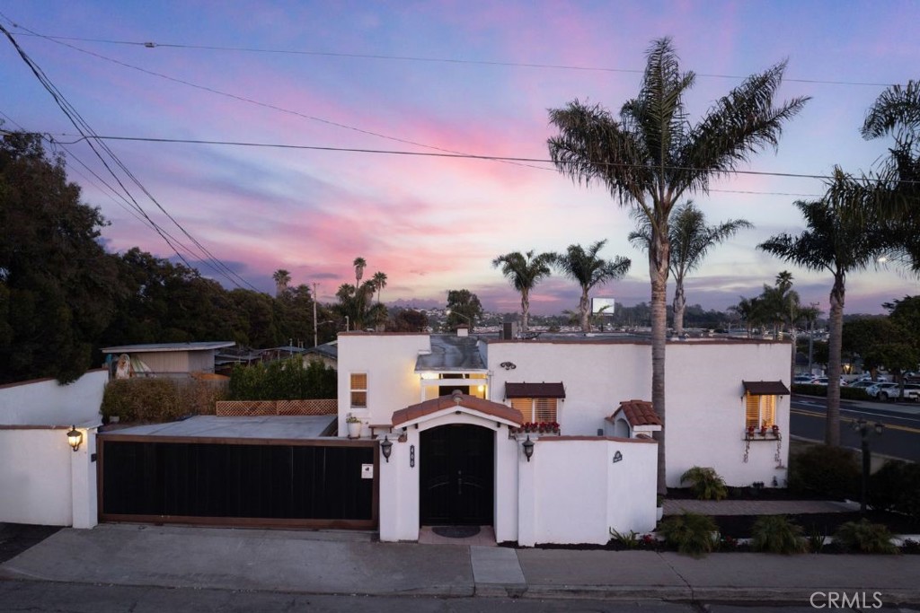 Situated in the vibrant heart of downtown Pismo Beach, “Casa de las Olas” is a beautifully updated Spanish-style residence offering exceptional flexibility, timeless character, and enviable proximity to all the Central Coast has to offer. Designed as a two-level home with dual living spaces, this property is ideally suited for vacation rental income, multigenerational living, or a luxurious coastal retreat. Each level features its own private entrance, along with a fully equipped kitchen, laundry area, bedroom, bathroom, dining area, and living room. A central staircase connects the units, but doors at either end can be closed off for enhanced privacy, allowing the units to function independently if desired. The upper level offers an additional lounge area at the rear of the home, perfect for gathering or relaxation. Both interiors showcase a tasteful blend of modern finishes and coastal elegance, complementing the home's classic Spanish architecture. The oversized lot offers enclosed-gated parking for up to 6 vehicles! The lot offers pedestrian and vehicle access—with keypad entry—provides added security and convenience, leading to a welcoming front entryway just steps from the driveway. From the upper level, enjoy sweeping views of the charming Pismo Beach landscape, along with peek-a-boo ocean vistas that hint at the surf and sand just steps away. Whether you're drawn to the lifestyle, the investment potential, or the architectural charm, this exceptional property captures the very best of beachside living.