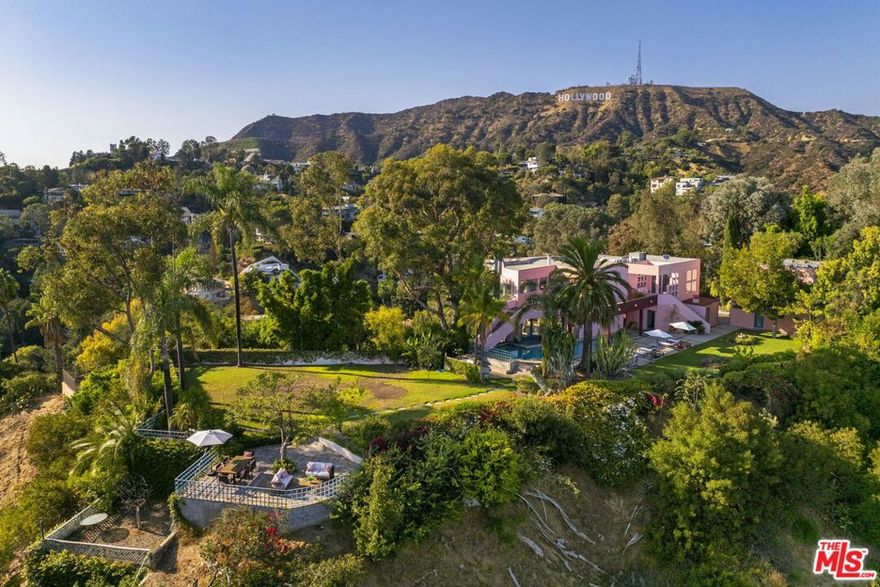 Outstanding opportunity to acquire an extraordinary 1+ acre compound featuring three separate structures set behind a gate at the end of a private driveway above Hollyridge Drive. The main residence, freestanding guest house, and separate studio above the detached garage provide an abundance of functional space in which to live, work, and entertain amidst a sprawling landscape affording a remarkable sense of privacy. Sited perfectly along a vast ridge and high above the canyon, you will marvel at the unobstructed views of the Downtown Los Angeles skyline, the Griffith Observatory, and the iconic "Hollywood" sign all visible from your own backyard. Distinctive1980's architectural designed by Michael Pearce and Richard Clemenson highlighting many of the characteristic details of the era, including large picture windows, glass block, bleached oak floors, a breezy pastel color palette, and multiple patios & terraces from which to take in the incredible 280-degree wrap-around vistas. The main residence consists of 3 bedrooms + 6 baths with a flex room and an upstairs loft currently configured as an entertainment space & office and poised for reimagination as a dramatic 2-room primary suite. Full separate guest house located at the opposite end of the property features a living room/lounge crowned with a dramatic atrium ceiling, kitchenette, 1 bedroom, 2 baths, and multiple French doors leading to assorted patios bordered by a canopy of trees and lush greenery. The expansive grounds consist of multiple outdoor areas including rolling lawn, a swimming pool, lounging decks, flower & cactus gardens, BBQ station, and a vast flat grassy pad providing the ultimate play area. Ideal for a developer, owner/user, artist, or rock star seeking privacy and the space to create an art or recording studio in a separate detached structure. The longtime home of legendary television writer/producer David Jacobs, creator of the classic drama series DALLAS and spinoff KNOTTS LANDING, who along with his wife and children, acquired a sequence of lots over a span of years to create this one-of-a- kind estate still brimming with possibilities and unlimited potential. Utterly unique & memorable.  No sign on property.