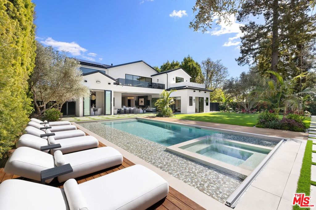 A triumph of exceptional design and masterful craftsmanship, this brand-new custom estate is a striking fusion of contemporary sophistication and organic warmth. Designed by the award-winning Gispan Design, it commands attention in one of Brentwood's most coveted enclaves on the rim side of the street. Spanning 11,270 square feet including a private 890-square-foot guest house, this residence effortlessly marries exquisite Italian-imported finishes with a layout that's perfect for grand entertaining while remaining deeply personal and inviting. The main level greets you with a stunning double-height foyer leading to a sprawling open floor plan. A formal living room, dining room and sitting room flow seamlessly together enhanced by a temperature-controlled wine cellar. The expansive family room with its soaring ceilings and sleek fireplace opens onto a covered terrace overlooking the lush backyard. At the heart of the home is the chef's kitchen - a true masterpiece featuring two distinct kitchens (one for everyday use and another catering-ready) complete with Italian-imported finishes, professional-grade appliances and custom cabinetry. A media room, office and two ensuite guest bedrooms complete the main level. Upstairs the expansive primary suite offers a true retreat featuring a fireplace, a spa-inspired bath with a soaking tub, dual vanities, an oversized shower, a private terrace and stunning canyon views. The custom-designed dressing room goes beyond the concept of a walk-in closet, offering a unique space that feels like a luxury boutique store complete with vast shelving and storage, curated lighting and meticulous craftsmanship that elevates everyday dressing into an extraordinary experience. Four additional ensuite bedrooms each with walk-in closets and designer bathrooms surround a sitting room with a balcony overlooking the lower level. The guest house is a luxurious independent retreat complete with a spacious living and dining area, a fully equipped kitchen and a private ensuite bedroom making it an exceptional space for visitors, extended stays or hosting in ultimate comfort and style. Designed for seamless indoor-outdoor living, the sun-drenched backyard is a private oasis featuring a large saltwater pool, lush lawn, multiple covered patios, a fire lounge and an outdoor kitchen with a BBQ and wet bar- perfect for both entertaining and relaxation. A one-of-a-kind offering, 115 S Rockingham Ave is a masterpiece of design and sophistication while effortlessly combining grandeur with the warmth and comfort of home.