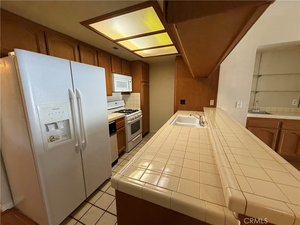 Los Caballeros: Upper 2 Bedroom 2 Bath, Living room With Pergo Flooring Throughout, Fireplace With Mantel, Separate Dining, Wet Bar, Kitchen With Tile Flooring, Tile Counter Tops, Breakfast Bar, Stove, Dishwasher, Microwave, Trash Compactor (AS IS), Refrigerator (AS IS) Bathroom With Tile Flooring, Bedroom With Mirror Closet Doors, Laundry Hook-Up’s With Washer And Dryer Included (AS IS), 1 Assign Covered Carport, Near Mile Square Park, Community Gated, Pool, Spa, And More.