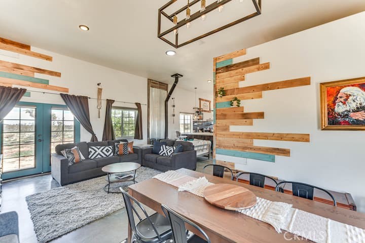This fully furnished 3 bed, 2 bath home with an open-concept layout and sleek concrete floors, offers modern touches with its rustic charm desert living. There are 2 bedrooms and 1 bath in the main house, and a separate 1 bed, 1 bath unit with it's own entrance—perfect for guests, mother in law, or rental income. Nestled right in front of Goat Mountain in Landers, enjoy stunning views and peaceful surroundings under the Milky Way and beautiful desert skies in the jacuzzi. 2 acres of the 5 acre parcel is fenced so that you ca have pets or kids can play without you worrying, and there is a tool shed and additional electrical panel for any future projects of expanding the property. La Copine, The Integratron, OHV area in Johnson Valley, Joshua Tree, Giant Rock, and more are just a few minutes drive, and there's a plethora of BLM land just out your back yard to the north east.