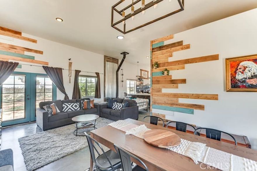 This fully furnished 3 bed, 2 bath home with an open-concept layout and sleek concrete floors, offers modern touches with its rustic charm desert living. There are 2 bedrooms and 1 bath in the main house, and a separate 1 bed, 1 bath unit with it's own entrance—perfect for guests, mother in law, or rental income. Nestled right in front of Goat Mountain in Landers, enjoy stunning views and peaceful surroundings under the Milky Way and beautiful desert skies in the jacuzzi.  2 acres of the 5 acre parcel is fenced so that you ca have pets or kids can play without you worrying, and there is a tool shed and additional electrical panel for any future projects of expanding the property.  La Copine, The Integratron, OHV area in Johnson Valley, Joshua Tree, Giant Rock, and more are just a few minutes drive, and there's a plethora of BLM land just out your back yard to the north east.