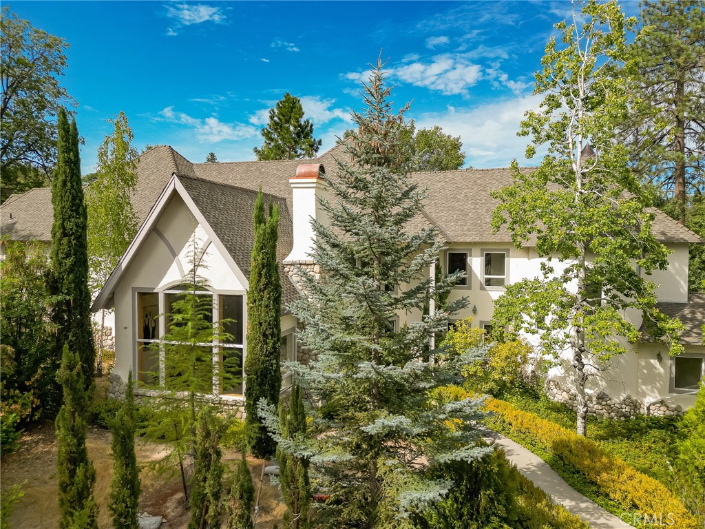 On nearly half an acre in one of Lake Arrowhead’s most sought-after neighborhoods near Tavern Bay, this 5-bedroom estate blends timeless elegance with modern comforts. Its castle-inspired exterior makes a striking first impression, opening into a grand foyer highlighted by a new granite accent wall. Inside, your great room centers around cathedral windows and a massive stone fireplace. Add walnut hardwood floors, fresh carpet, and a thoughtful floor plan that set the stage for refined mountain living.
The home offers two primary suites—one with a walk-in closet and fireplace—along with a newly added game room (or potential ADU), formal dining room, and a chef’s kitchen featuring a Sub-Zero refrigerator and freezer, walk-in pantry, and ample prep space. Off the dining room, find your opportunity to create a future wine room.
While this residence already boasts striking architectural presence and generous updates, it also presents a chance for its next owner to bring the finishing touches that will make it truly extraordinary.
The attached three-car garage, nearly half-acre grounds, and proximity to Tavern Bay Beach Club and the UCLA Conference Center make this estate both a private retreat and an entertainer’s dream—an impressive canvas awaiting your personal vision. Yes, it has lake rights.