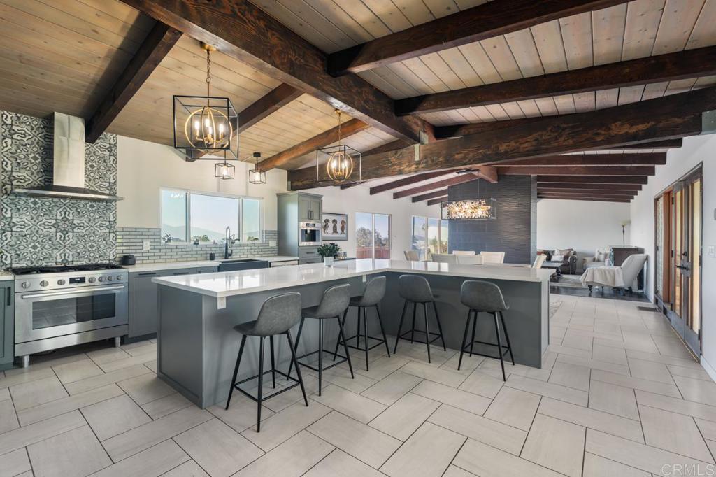 Nestled in the hills of Mt. Helix, this beautifully reimagined 5-bedroom, 2.5-bathroom mid-century multi-level home offers a perfect blend of timeless architectural charm and elevated modern living. Boasting 3,484 sq ft of interior space on nearly half an acre (.48 acres), this property delivers flexibility, privacy, and panoramic views in one of East County’s most desirable enclaves. Step inside to soaring beamed ceilings and an open-concept great room with picture windows that flood the home with natural light. The renovated chef’s kitchen is the heart of the home, featuring a dramatic oversized island, designer backsplash, premium appliances, and sleek cabinetry—ideal for entertaining or culinary inspiration. Gather in the spacious dining area or unwind in the cozy living room with a show-stopping fireplace and floor-to-ceiling views of the mountains beyond. Outside, a wraparound deck creates the perfect perch to sip your morning coffee or dine al fresco while taking in sweeping views of the lush landscape and surrounding hillsides. The expansive lot offers room to explore, garden, or even build a potential ADU (Accessory Dwelling Unit) or a pool. The terraced yard offers charm and opportunity for outdoor play, fruit trees, or hillside landscaping. Upstairs, retreat to the spacious primary suite with serene vistas and a spa-like bathroom. The home’s flexible layout also lends itself to multi-generational living or a home office setup—perfect for today’s evolving needs. Located in the prestigious Mt. Helix community of La Mesa, you’ll enjoy the best of quiet suburban living with close proximity to shopping, dining, top-rated schools, and freeways. Don’t miss your chance to own this rare, view-filled mid-century beauty in one of La Mesa’s most sought-after neighborhoods.
