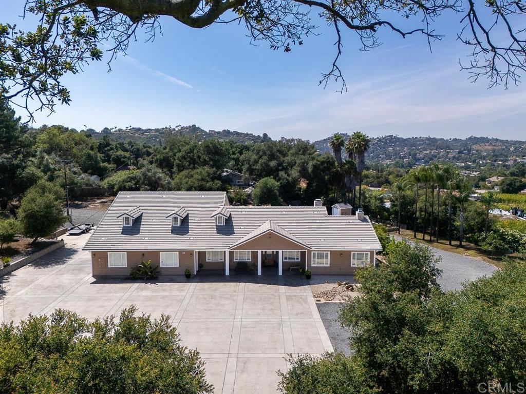 This custom home is one of kind and rarely available you need to view to appreciate the upgrades with lots of opportunity on 1.63 acre on usable lot for ADU or guest house low maint. landscaping this custom home offers privacy and fully fenced with one of a kind garage. Welcome to your dream home at Rancho Roble, a private gated custom estate nestled in the serene community of Escondido. Need space for cars, construction vehicles, recreational vehicles or simply need space and privacy look no further this home has you covered this dream 6+ garage can accommodate a car lift, RV or Boat with ease. This impeccably maintained residence with large level lot offering privacy, luxury, and room to expand As you arrive, a custom iron gate opens to a long private driveway that can accommodate more than 12+ vehicles with ease beautifully low landscaped grounds. The custom front door, crafted from alder wood and glass, leads into a thoughtfully Single-level living with 4 bedrooms + upstairs bonus room 5th bedroom/guest suite with private half bath. As you open the doors your greeted with soaring ceilings with custom Faux wood beams and views to your backyard. The 5th bedroom upstairs is ideal for guest, multi-generational living or in-law quarters Gourmet kitchen with quartzite countertops, Viking range, stainless steel appliances, upgraded fixtures, and a spacious island perfect for entertaining New custom quartzite stone enclosure on all bathrooms and vanities, Large baseboards, newer flooring, and fresh interior paint Dual walk-in closets in the primary suite and dual-zone HVAC systems Ample attic storage and built-in fire safety features including cement siding, enclosed fascia, indoor sprinklers, and exterior high pressure hose. Garage + RV/Boat Space: Custom 6 + car garage with center BAY garage ideal for car lift, RV or Boat. This dream garage can easily accommodate 6–7 vehicles lots of lighting for collectors or hobbyists in addition to large garage home has a dedicated RV parking space Outdoor Living: Entertainer’s backyard with expansive outdoor kitchen, built-in BBQ, fire pit, and multiple seating areas Fruit trees, vegetable garden, and scenic views of Escondido’s rolling hills This property offers the best of country living with high-end finishes and turnkey condition — a rare opportunity to own a fully upgraded home with space, privacy, and thoughtful design.