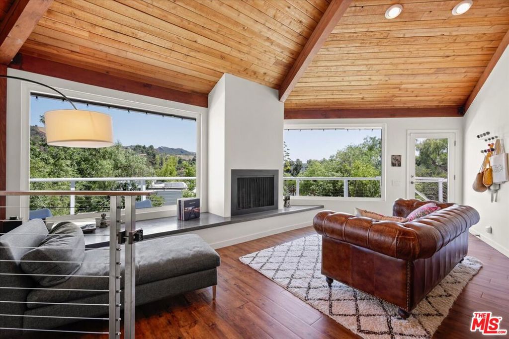 Available furnished or unfurnished. Welcome to this architecturally distinctive home, thoughtfully designed as a true retreat and quietly nestled in the heart of Topanga. Set on a spacious, newly landscaped lot, this 3 bedroom, 2 bathroom home blends architectural charm with seamless indoor-outdoor living. Inside this striking octagon-shaped home, vaulted cedar-beamed ceilings soar above expansive windows that capture mountain and canyon views, flooding the space with natural light. A cozy fireplace anchors the open living area, which flows onto a wraparound deck ideal for sunrise coffee or unwinding at sunset. The kitchen is outfitted with granite countertops and stainless steel appliances and opens directly to the main living areas, making it ideal for both entertaining & everyday living. The private backyard oasis features a hot tub and new landscaping with fully enclosed rattlesnake fencing. Whether you are soaking in the hot tub beneath the stars or strolling through the garden, every corner of this property invites a sense of calm. Located just a short walk to Topanga Living Cafe and nearby hiking trails, this home offers the perfect blend of nature and convenience. It feels worlds away while still being just minutes from both the coast and the valley. Additional features include a two-car garage, EV charger, and generous parking in the driveway. This inviting canyon sanctuary is ready for its next chapter!
