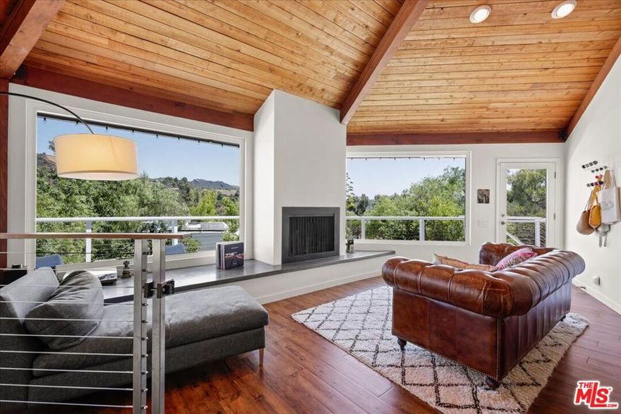 Available furnished or unfurnished. Welcome to this architecturally distinctive home, thoughtfully designed as a true retreat and quietly nestled in the heart of Topanga. Set on a spacious, newly landscaped lot, this 3 bedroom, 2 bathroom home blends architectural charm with seamless indoor-outdoor living. Inside this striking octagon-shaped home, vaulted cedar-beamed ceilings soar above expansive windows that capture mountain and canyon views, flooding the space with natural light. A cozy fireplace anchors the open living area, which flows onto a wraparound deck ideal for sunrise coffee or unwinding at sunset. The kitchen is outfitted with granite countertops and stainless steel appliances and opens directly to the main living areas, making it ideal for both entertaining & everyday living. The private backyard oasis features a hot tub and new landscaping with fully enclosed rattlesnake fencing. Whether you are soaking in the hot tub beneath the stars or strolling through the garden, every corner of this property invites a sense of calm. Located just a short walk to Topanga Living Cafe and nearby hiking trails, this home offers the perfect blend of nature and convenience. It feels worlds away while still being just minutes from both the coast and the valley. Additional features include a two-car garage, EV charger, and generous parking in the driveway. This inviting canyon sanctuary is ready for its next chapter!
