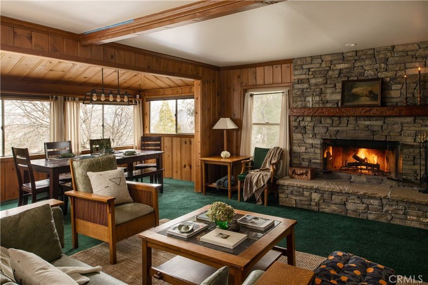 Perched above the trees and just moments from the towns of Lake Arrowhead and Cedar Glen, this level entry vintage gem with treetop and lake views is the perfect cozy retreat. Perfect for full-time living or part-time use, this home is also a successful short-term rental with an active Airbnb license—making it a turnkey investment opportunity. Elements of thoughtfully curated and elevated design details create a unique experience. Upon entry, an oversized mudroom with terracotta floors and wall-to-wall windows provides ease of use for every season and an abundance of storage. Through the charming kitchen with oak floors and an island is the open concept and spacious living area with a cozy wood burning stone fireplace, tongue and groove pine throughout and a charming window seat among custom built-ins. Enjoy meals in the dining space with a breathtaking wall of windows and views. The first guest bedroom is tucked away with wraparound windows creating a luxurious space with extra privacy. An additional bedroom and the sweet vintage bathroom complete the first level. A gorgeous hand-built solid wood spiral staircase is a work of art in this home. This alluring piece of craftsmanship leads you to the large primary bedroom with a bay window seat open to a private patio. The outdoor space is abundant with two separate seating areas and situated on a rare double lot, the expansive open space next to the home offers endless possibilities for expansion or customization. This turnkey offering provides peaceful mountain living near numerous hiking trails, the famous malt shop, Cedar Glen Inn, Mag. Pi, Cedar Glen Fine Foods grocery and much more!