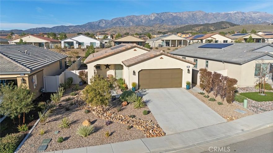 Welcome to this immaculately kept home that is better than a model, with all the improvements already completed for the buyer, located in a vibrant 55+ resort-style community where every day feels like a vacation and set against a stunning mountain backdrop. This nearly brand-new residence offers 2 spacious bedrooms, 2 full bathrooms, and a versatile office nook ideal for working from home or hobbies, along with a beautifully appointed kitchen featuring soft close cabinetry, light countertops, decorative glass backsplash, walk-in pantry, vaulted ceilings, and recessed lighting throughout, creating a bright and inviting space for everyday living and entertaining. The highly upgraded backyard is designed for low-maintenance outdoor enjoyment and includes an Aluma-wood patio cover with accent lighting and ceiling fan, privacy hedges, peek-a-boo mountain views, artificial turf, river rock along the side yard, and a mobile vegetable garden with an integrated watering system, while the front yard showcases drought-tolerant landscaping with an elegant river rock design. Additional highlights include solar panels for enhanced energy efficiency, making this home a perfect blend of comfort, style, and convenience in a premier community offering amenities designed for relaxation, social connection, and active living—truly a move-in-ready opportunity not to be missed.