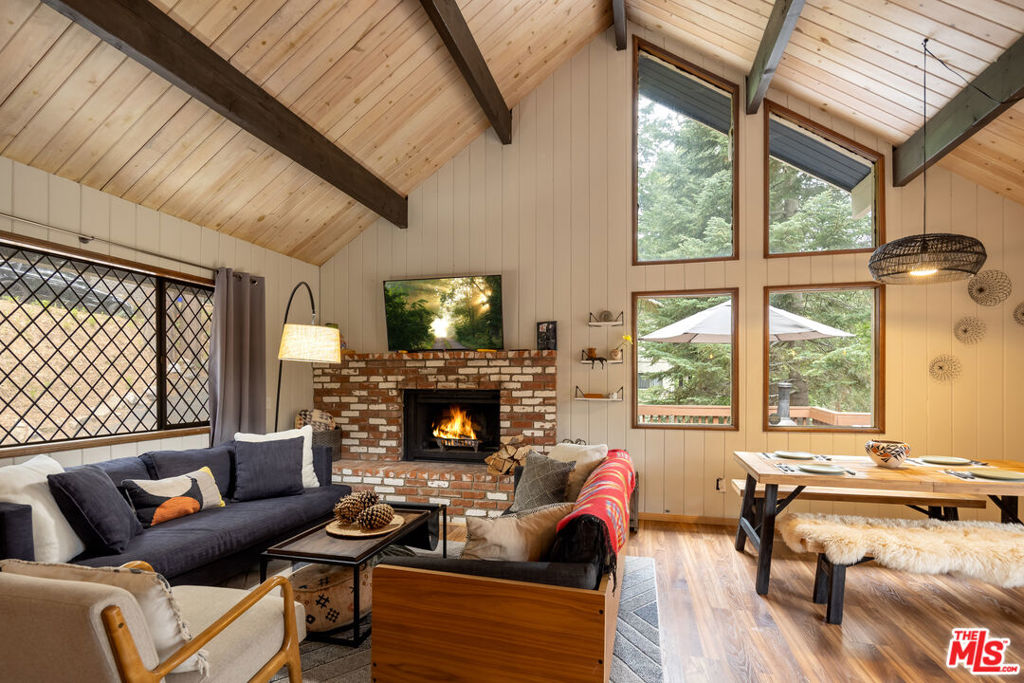 Welcome to your private and peaceful mountain retreat, nestled among the trees. Set in a quiet, serene location, this inviting home blends warm, rustic charm with modern touches. Soaring wood-beamed ceilings and a cozy fireplace create a welcoming atmosphere, while the wrap-around deck is perfect for barbecuing and enjoying a meal while stargazing at night. The property has been recently updated throughout, and can be available furnished. Currently enjoyed as a weekend escape, the home also holds a short-term rental permit, offering a turnkey opportunity whether you're seeking a home for yourself or a ready-to-go investment property. On the main floor, you'll find one bedroom, a full bathroom, and the main living area along with the open kitchen. Downstairs, the primary suite and third bedroom offer added privacy and comfort. The attached oversized garage (22x22 ft), a rare option in this area, with 10-foot ceilings, serves as both a practical parking space and an entertainment area, complete with a full-sized pool table. Whether you're hiking nearby trails, spending the day at Lake Arrowhead or Lake Gregory, or simply unwinding at home, this fully furnished property is move-in ready and perfectly suited for easy, laid-back mountain living. ***Disclaimer: Some photos have been virtually staged(TV screens, fireplaces, etc)***