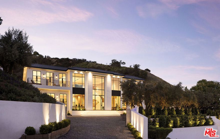 Set on one of Bel Air's most coveted ridgelines, Oliveto Vale presents a rare opportunity to own a refined contemporary estate with sweeping canyon and city vistas. Quietly positioned amidst peaceful olive trees above the Bel Air Country Club, this architectural residence blends clean modern design with effortless indoor/outdoor living across its sun-filled open floor plan. Expansive walls of glass frame treetop and skyline views, while multiple terraces create an ideal backdrop for entertaining or serene retreat. The main level features generous living and dining areas anchored by a sleek gourmet kitchen with premium appliances and a large center island. The primary suite serves as a private sanctuary with a spa-inspired bath, walk-in closet, and direct access to the outdoor living spaces. Additional bedrooms are well-scaled and thoughtfully placed for comfort and privacy. The outdoors offer tranquil California living at its finest, with a sparkling pool, lush landscaping, and view-oriented lounging spaces. Moments from Westwood, Holmby Hills, Beverly Hills, and premier schools, this Lower Bel Air residence combines exclusivity, elegance, and the timeless Bel Air lifestyle. Named for the verdant olive grove, a symbol of peace, wisdom, and renewal for countless generations, Oliveto Vale promises enduring abundance and a life well lived. A masterwork piece by Sharon Ohana of CDH Builders with architecture and design by Mike Khalesi of Beverly Hills One.