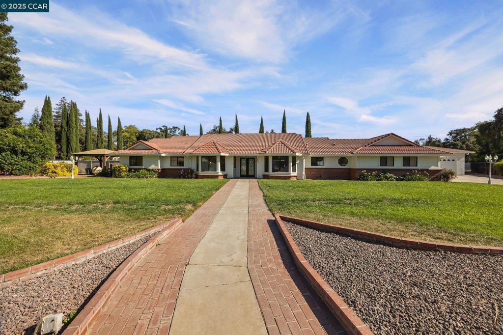 Welcome to this fully remodeled ranch-style estate in the highly sought-after Morada area, perfectly positioned at the end of a quiet cul-de-sac for ultimate privacy. Set on a gated, beautifully landscaped 3/4 acre parcel that feels like a private park, this property offers a rare combination of elegance, space, and versatility. This home has been thoughtfully renovated, making it feel like new. The gourmet kitchen is a chef’s dream, featuring polished granite counters, crisp white cabinetry, and high-end finishes. The open living area, accented by a striking fireplace, flows into a chic bar area—perfect for entertaining. Step outside to your private backyard retreat, complete with a sparkling pool, large grilling area, greenhouse and garden space, expansive lawn, and mature trees that create a serene, resort-like atmosphere. Whether you’re hosting summer gatherings or enjoying a quiet swim, this backyard is made for both relaxation and fun. You'll love the two-car garage plus an extra-large detached one-car garage with RV outlet hookups—ideal for a workshop, gym, or more! Paid-off solar and a long, concrete driveway provide ample parking for 10+ vehicles, RVs, or boats. Just minutes from Lodi Wine Country, enjoy Morada’s quiet charm while staying close to everything you need