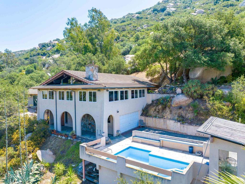 Incredible private mountain retreat surrounded by nature. Gorgeous oaks and giant boulders. Rock entry walkway with lovely pool and spa. Covered area to entertain. Custom home 3 bedroom, 2 3/4 bath with hand hewn open beams throughout. True craftsmanship. Spacious living room with rock fireplace and bar. Enclosed patio room with hand cut stone flooring. Very large master bedroom has lovely views of the canyon. Bilevel floor plan. Large kitchen, lots of food prep counter space. Breakfast bar. Extra entry level room has 3/4 bath. Lots of storage area. Separate guest house has one bedroom, kitchen and detached garage. Experience a special unique lifestyle seldom found so close to all. A true gem hideaway located minutes from Temecula, numerous wineries, entertainment, shopping and the I-15 freeway.