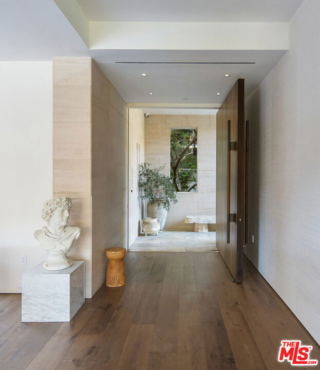 An architectural triumph in Brentwood's exclusive Mandeville Canyon, this newly completed estate rests on a 13,939 SF lot, commanding breathtaking, uninterrupted views of the San Gabriel Mountains and city. Seamlessly harmonizing with its tranquil natural surroundings, this six-bedroom, twelve-bathroom residence has been masterfully curated to balance grand-scale entertaining with intimate tranquility, showcasing bespoke design and unrivaled craftsmanship at every turn.The journey begins with the soothing sounds of a garden water feature, along a stone-paved entry framed by lush tropical greens and the seclusion of gated privacy. A dramatic, ceiling-height pivot door and beautifully wood-paneled floating staircase transcend elegance, as you step into the open floor plan, where floor-to-ceiling windows and expansive pocket doors effortlessly connect the indoors with the outdoors. This resort-like retreat leaves the bustle of Los Angeles behind, with the formal living room and custom fireplace flowing into the dining room and a poolside patioperfectly suited for both intimate gatherings and grand entertaining. Adjacent to the family room, the heart of the home reveals a chef's kitchen, featuring an Ilve Majestic range and ovena work of art in its own rightalongside a Wolf appliance suite, a glass-door Monogram refrigerator, and a Sub-Zero wine fridge. A breakfast dining nook and a cozy lounge with its own fireplace extend the warmth of this space, leading to a grassy patio complete with an outdoor kitchen, BBQ, and bar. Hanging greenery cascading over balconies enhances the home's organic architectural character, while panoramic pocket doors frame breathtaking hillside and mountain vistas. A sparkling infinity edge pool/spa and skillfully conceived landscaping make this remarkable residence feel like a private oasis. Upstairs, vaulted ceilings crown a landing that opens to a spacious balcony. Each bedroom boasts gorgeously crafted, Belgian wall treatments, while an office and additional guest bedroom share a large patio that offers uninterrupted hillside views. The primary suite is an indulgent escape with a stone fireplace, an expansive walk-in closet, and dual bathrooms featuring a soaking tub, a white rose quartz rainfall shower, and a personal viewing terrace that feels sky-high. The lower level is dedicated to wellness and entertainment. A glass-encased fitness studio and a spa-inspired wellness room include a steam shower, sauna, and spacious massage area. A private guest suite opens to a large terrace with room for a game table and lounge, while a glass-enclosed wine room and regal library/office add a sense of incomparable opulence. A massive screening room with a custom-built bar completes this level, creating a haven for relaxation and leisure. Other notable features include a 3-car garage, ample storage throughout, and a convenient elevator providing easy access to all levels of the home.This property's exceptional design is matched only by its prime location in Brentwood's prestigious Mandeville Canyon, within close proximity to the Westside's best school districts, shopping, dining and nightlife. A truly one-of-a-kind marvel, elevated even further by the current owner's impeccable taste and artful design choices.