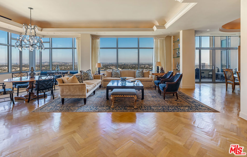 Along the famed Wilshire Corridor, this 5,056sf penthouse in the sky offers 2 bedrooms, 3 bathrooms, 2 powder rooms and a separate 568sf private housekeeper's unit. A dedicated elevator opens into a sophisticated foyer that immediately reveals sweeping vistas from Century City and downtown to the hills, marina, and the Pacific beyond, stretching out in every direction through expansive windows. The open floor plan features a grand formal living room with twelve-foot soaring ceilings, soft cove lighting and a built-in bar that creates a refined setting for entertaining. Every room is thoughtfully positioned to capture the sweeping 180-degree views. The formal dining room boasts twelve-foot ceilings, a dramatic oval recessed cove and cobalt Viennese plaster walls. Designed for elegant gatherings, it comfortably seats ten and opens to a private terrace. The gourmet kitchen features a bold blue granite island, top-tier appliances, a breakfast area, built-in desk, wine fridge and a butler's pantry. A distinguished den features rich wood-paneled walls, custom built-in cabinetry and shelving and a black marble fireplace. An adjoining office completes the space. Double doors open into the sumptuous primary suite, where serene panoramic views envelop the space, along with a cozy fireplace, inviting sitting area and private terrace. The suite boasts dual luxurious bathrooms, each with spacious walk-in closets and custom countertops, one featuring an Azul Cielo stone soaking tub overlooking the city, and the other adorned with rich wood finishes. A sophisticated guest bedroom suite completes this private wing. Additional luxurious highlights include dual private elevators, Herringbone oak floors run throughout, ample storage, motorized blackout shades and a state-of-the-art Lutron system. A separate, private corner housekeeper's suite offers a full bath, sleeping area, kitchenette and dual exposures with windows on two walls, providing both comfort and natural light. The Californian's luxurious full-service amenities include 24/7 security and valet, on-site manager, ample storage, a state-of-the-art fitness center, temperature-controlled wine cellar, and a heated pool and spa nestled within landscaped gardens. A rare offering in one of L.A.'s most prestigious buildings, this penthouse blends sweeping city-to-ocean views with timeless design and effortless luxury. Both expansive and intimate, it's a serene sanctuary for those who value beauty, privacy, and the art of elevated living above the city.