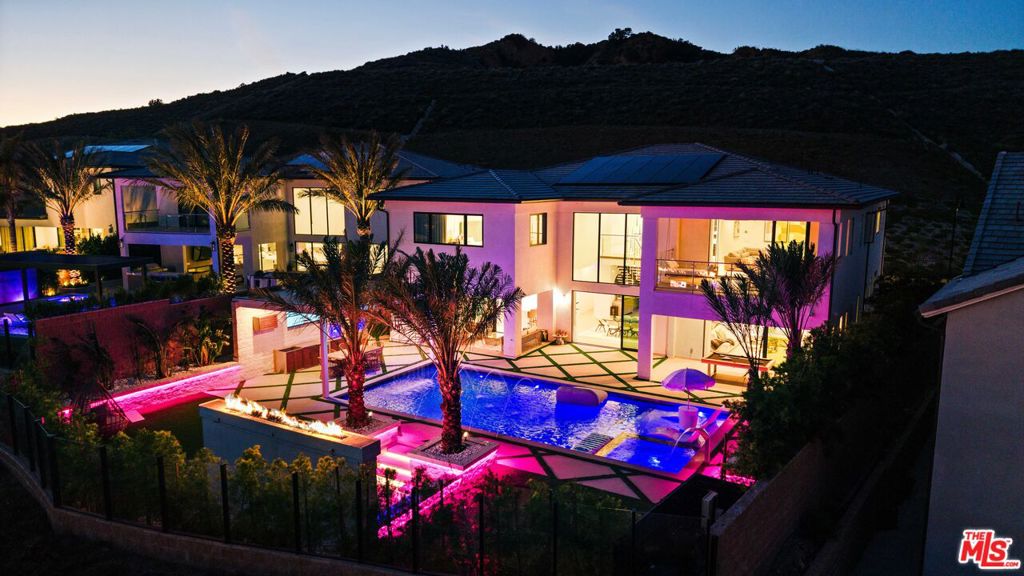 Perched atop the prestigious guard-gated community of Westcliffe at Porter Ranch, this exceptional estate redefines luxury with an unmatched blend of sophistication, comfort, and breathtaking design. From the moment you arrive, the grand custom gated driveway welcomes you to a residence of rare distinction, framed by sweeping mountain views and unparalleled privacy.Step inside to discover a stunning architectural masterpiece featuring dual floating staircases that make an unforgettable statement beneath soaring ceilings. Every detail of this home has been thoughtfully curated from premium in-ceiling speakers throughout, rich hardwood floors, and upgraded designer carpet in all secondary bedrooms, to the expansive office adorned with French glass doors and custom built-in cabinetry, creating a space that's both refined and functional.The home offers four generously sized secondary bedrooms, each complete with custom built-in closets and spa-inspired en-suite bathrooms, providing comfort and privacy for family and guests alike. The primary suite is a true retreat, showcasing sweeping city views, an oversized custom walk-in closet, and a tranquil ambiance that elevates everyday living.At the heart of the home lies the gourmet chef's kitchen, outfitted with top-of-the-line Wolf appliances, a large walk-in pantry, and seamless flow into the living and entertaining areas an entertainer's dream come to life.Step outside to your private resort-style oasis: a sparkling pool and spa, sunken fire pit, putting green, and pergola with a cascading rainfall water feature. The gourmet outdoor kitchen comes fully equipped with a TV, beverage refrigerator, and top-tier BBQ setup, perfect for unforgettable evenings under the stars.Additional features include a converted gym in the spacious garage, offering the flexibility and luxury of a full wellness space at home.This is not just a home it's a statement. A sanctuary. A rare opportunity to live at the pinnacle of Porter Ranch in one of its most coveted locations.