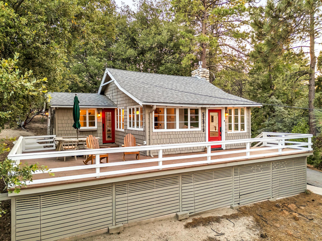Escape to this beautifully reimagined woodland retreat nestled on a serene and private .61-acre lot with captivating forest views. This 2-bedroom, 1-bath home has been completely renovated with meticulous attention to quality and detail. Inside, enjoy new flooring throughout, a cozy new gas fireplace insert, shiplap interiors, and Circa Lighting fixtures. The brand-new kitchen features a gas range, farmhouse sink with high-end Perrin & Rowe brass bridge faucet, Acacia wood butcher block counters, custom distressed range hood, and built-in dining with banquette seating. The spa-like bathroom boasts a $6,000 soaking tub, Carrera marble shower and floors, and a skylight. Additional spaces include a laundry/mudroom, an office or studio, and a separate artist's studio. French doors, glass transoms, and ceiling fans enhance the natural light and air flow. Major system upgrades include A/C, a newer roof, plumbing, electrical, furnace, and piers. Outside, enjoy expansive decks, newer exterior paint, new lighting, and a charming potting shed or Artist's studio with new structural improvements. A peaceful, turn-key mountain getaway, wired for modern living yet steeped in rustic elegance.