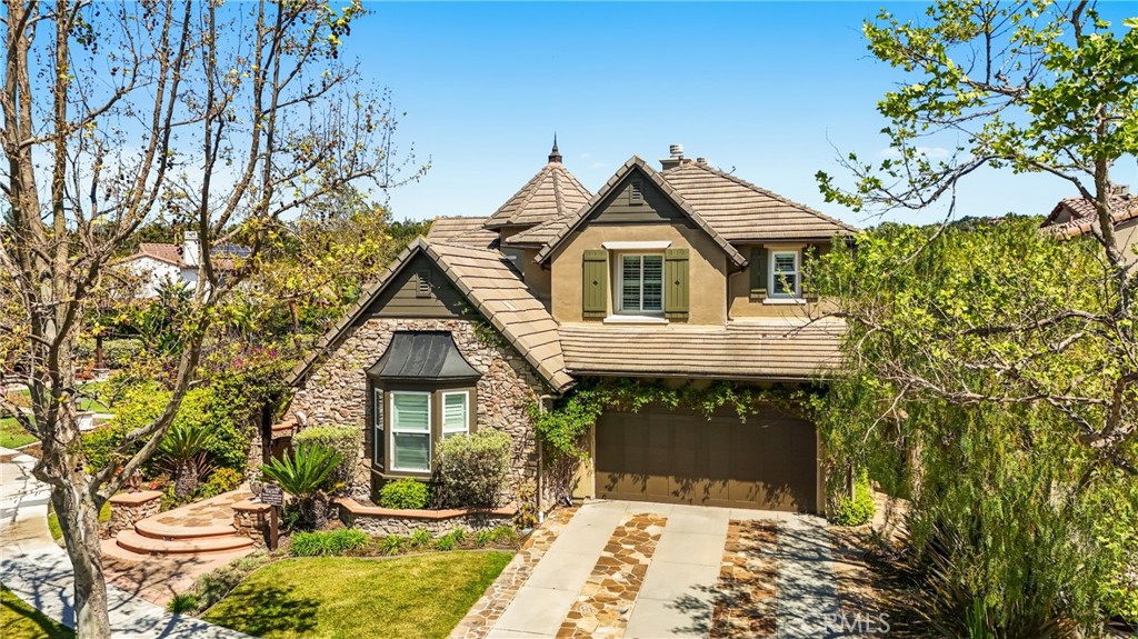 Welcome to this beautifully crafted French country-inspired estate, located at the end of a peaceful cul-de-sac and next to a tranquil greenbelt, offers a blend of luxury, comfort, and convenience. The impressive courtyard sets the tone, inviting you to step inside and experience the warmth of a romantic outdoor fireplace hearth.
The main living areas include expansive formal living and dining rooms, an open-concept kitchen with a central island, stainless steel appliances, and a cozy breakfast nook. The adjoining family room offers ample space for relaxation, and the lower level includes a generously sized guest en-suite bedroom.
Upstairs, a grand Cinderella staircase leads to a magnificent master suite, complete with a private balcony offering scenic views. The luxurious master bath features intricate leaded glass windows and custom finishes. Two spacious ensuite bedrooms, along with a large loft area equipped with built-ins, a decorative balcony, and a convenient hobby niche, complete the upper level.
The private Casita could easily be converted into yet another bedroom. Throughout the home, custom millwork, arched doorways, trim, and built-in cabinetry add both elegance and practicality. The finishes include natural stone floors, elegant granite countertops, custom wood cabinetry, tailored window treatments, and neutral paint tones that enhance the home’s timeless appeal.
The rear grounds are perfect for entertaining, with a built-in BBQ island, seating area, and a lovely ambiance. A three-car tandem garage with epoxy flooring completes this dream estate, making it the perfect home for any discerning buyer. Conveniently located near schools, a clubhouse, sports courts, a water park, and the central paseo, this estate offers both privacy and accessibility. 24 Hour guarded Covenant Hills Community offers the Best in Orange County Living.