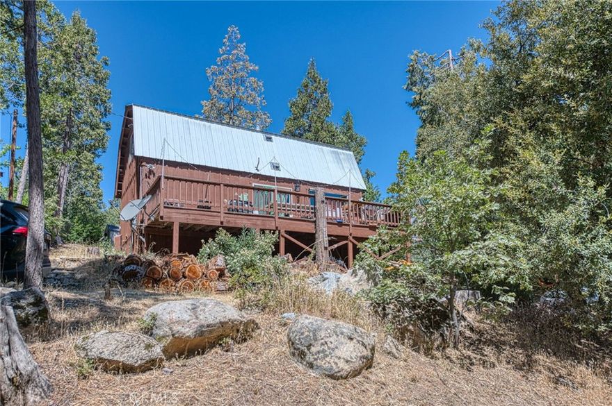 Tucked away at the end of a quiet lane in the Meadow Lakes subdivision, this charming two-bedroom, one-and-a-half-bath cabin offers just under 1,100 square feet on the main level, plus two bedrooms and a bathroom upstairs. The updated living space on two adjoining lots totaling more than 10,500 square feet. The interior blends rustic warmth with modern upgrades, featuring a freshly updated kitchen, stylish new tile and carpet, ample storage under the stairs, and a convenient laundry/bath combo on the main floor. Upstairs, both bedrooms offer peaceful treetop views. The sweeping front deck overlooks local wildlife and endless stars, providing a perfect space to relax, dine, soak in your private hot tub, or entertain beneath the pines. A free-standing wood-burning stove adds cozy ambiance on cooler evenings, and the sturdy wood shingle siding, metal roof, and gleaming wood flooring offers long-term durability. With a dual-lot layout enhancing privacy and potential, and a covered platform perfect for glamping or storage, this property invites endless possibilities, whether as a primary residence, a weekend getaway, or a creative investment. Residents enjoy access to a private recreational lake and shared open spaces for outdoor leisure. Auberry is a peaceful, quiet town - under an hour away from Fresno - nestled in the Sierra Nevada foothills. Located near Shaver Lake, Auberry is best known for stunning views of nature and outdoor activities. FHA and USDA ready! This property will be a short sale, subject to lender approval.