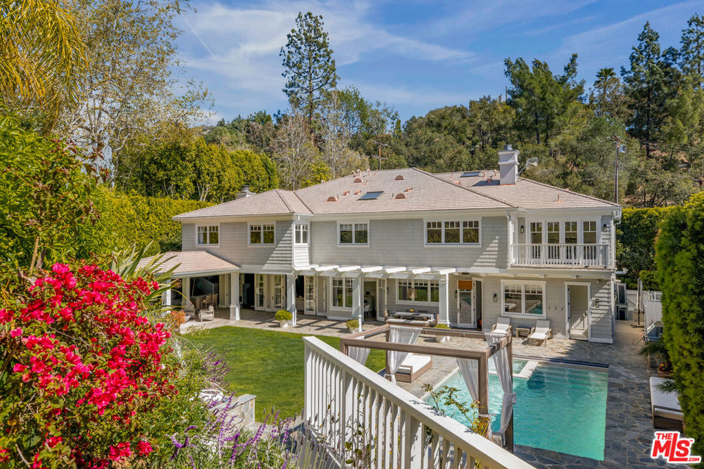 This charming Cape Cod estate, a sanctuary of peace and privacy, is nestled behind tall hedges with a gated entry, set on over half an acre of meticulously landscaped gardens. Designed by acclaimed architect, Ken Ungar, the home combines traditional elegance with practical, easy living, offering the ideal setting for both relaxation and entertainment. Inside, the spacious and light-filled interiors feature high ceilings, creating an open, airy atmosphere throughout. The home boasts six generously sized en-suite bedrooms, a study, a bar, a children's media and playroom, and a tranquil yoga room, perfect for unwinding or staying active in the comfort of your own home. Notably, five bedrooms are located upstairs, including an exceptional primary suite with dual walk-in closets and a luxurious bathroom. The seamless flow of the living areas ensures comfort and convenience, with ample space for both formal and informal gatherings with large living room, and a separate dining room. A spacious chef's kitchen with high-end appliances, walk-in pantry, and butler's pantry with full height wine fridge, breakfast nook and command center. Bespoke walnut flooring flows throughout the home. A playhouse, painted to match the main house, sits at the top of the landscaped gardens with fruit trees and enclosed vegetable bed overlooking the large lawn, along with a saltwater pool and spa, covered seating, and integrated barbeque, perfect for outdoor entertaining. This is a fully smart home throughout with three-car garage. Designed with both style and functionality in mind, this home offers the perfect balance of practicality and elegance.