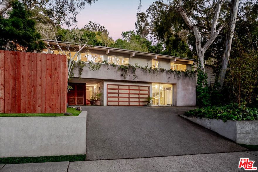 Beautiful midcentury architectural retreat in Rustic Canyon. Set on an expansive approximately 17,522 sq ft lot, this serene, light-filled four-bedroom, five-bath home showcases floor-to-ceiling glass for effortless indoor outdoor flow. Enter through a hand-carved wood door to a flexible lower level with a large bedroom or media room on the left and a three-car garage currently converted to bonus space on the right, ideal for studio, office, or gym. Warm natural finishes include a stone fireplace, skylights, and beamed ceilings. Upstairs, the sunlit kitchen and family room open to patios and a pool; three additional bedrooms, including the primary suite, are on this level, and all bedrooms feature ensuite baths. The bright kitchen overlooks a sunny pool framed by mature trees and lush landscaping. The property faces the protected historic Eucalyptus Grove and sits next to Rustic Canyon Park with twelve public tennis courts, a basketball court, playground, community center, and picnic lawns. Enjoy tranquil country living close in with ocean breezes and quiet tree-lined streets, minutes to the beach, Palisades Village, and Montana Avenue shops and dining.