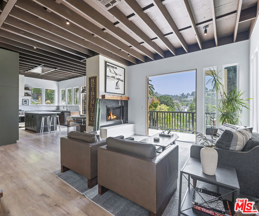 Experience the perfect blend of Hollywood Hills luxury and downtown loft sophistication in this completely remodeled and redesigned two-story contemporary 4-bedroom, 3-bath architectural gem. Perched in the hills yet infused with an urban edge, this open and airy home offers expansive living spaces bathed in natural light, high ceilings, and warm organic finishes that create a true one-of-a-kind atmosphere. The soaring 10-foot exposed ceilings immediately create a sense of openness, complemented by natural wood beams and thoughtfully placed lighting. The gourmet kitchen features all new premium stainless appliances, custom cabinetry, and a spacious island perfect for entertaining. The primary suite is a private oasis featuring a spa-like ensuite bath, walk-in closet, and floor-to-ceiling glass doors that open to serene canyon vistas. Three additional bedrooms and a bonus room offer versatility for family, guests, creative studios, or home offices. Outside, multiple terraces and patios offer seamless indoor-outdoor flow perfect for morning coffee, evening cocktails, or alfresco dining under the stars. Located just minutes from downtown Hollywood and major studios, this home delivers the best of both worlds: a tranquil escape with the pulse of LA at your fingertips. Available furnished or unfurnished...short or long term.