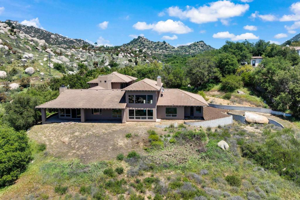 90% Financing available, Breathtaking Panoramic View Home Perched high above the valley on over 25 acres of pristine land on Ramona's West end. This one-of-a-kind, custom-designed estate offers views stretching across Lake Poway, North Poway, Rancho Bernardo, and all the way to San Diego’s coastal horizon. With 4+ bedrooms and 5 baths, this architectural gem is awaiting your finishing touches to make it complete. Designed to impress, this estate features wide 5' hallways, elegant travertine floors, granite countertops, and a stunning "Romeo and Juliette" indoor balcony. Entertain with ease in the spacious kitchen, complete with a Butler’s Pantry. The grand bonus room above the garage has over 1,000 sq ft with hardwood plank flooring, a private deck, and is prewired for a home theater and kitchenette. Car enthusiasts and hobbyists will love the expansive garage with three 10'x8' insulated roll-up doors and approx. 27' of depth. Home includes dual hot water heating systems and a central vacuum system. A rooftop observation deck, affectionately known as the "Hawk’s Nest," offers a perfect perch to take in sunset skies and star-filled nights. Ask about the tax incentives on making this a vineyard estate. Pool/spa area was planned, but not finalized. Bring your luxury landscaped oasis to life.