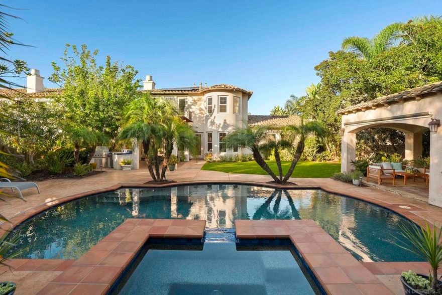 Experience resort-style living in this stunning luxury home, located in the highly sought-after, guard-gated community of Santa Monica directly across from the Santaluz Club. This exceptional property features a tropical backyard oasis highlighting a saltwater pool and spa, large lawn, built-in BBQ, lush landscaping, and a separate cabana with fireplace, wet bar, beverage cooler and convenient pool bath. Additional features include Viking appliances, a family kitchen with large center island, an impressive temperature-controlled 900+ bottle wine cellar, paid solar, and built-in surround sound throughout the interior and exterior. Secondary living and bonus rooms open to a private side courtyard for the ideal indoor/outdoor experience, while the luxurious master suite includes a fireplace, sizable private balcony, dual custom walk-in closets, and a separate vanity counter, soaking tub and shower. Architectural details such as large wood beam ceilings in the formal dining, crown moldings and custom built-ins add elegance throughout. The home also offers several additional rooms, offices & dens providing flexible spaces that can tailor to any lifestyle. Residents of the Santa Monica community enjoy top-tier amenities including tennis and pickleball courts, a basketball court, sand volleyball court, resort-style pool and spa, fitness center, BBQ, playground, picnic areas, along with access to miles of scenic hiking trails. This home is not one to miss!