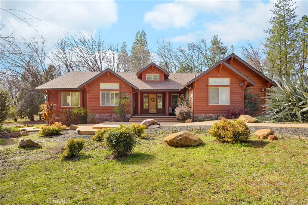 Nestled in the heart of the mountains, this custom-built craftsman-style lodge sits on a stunning level 3-acre lot surrounded by majestic oak, cedar, and walnut trees. With amazing curb appeal, the home is easily accessed via a paved county road and a concrete driveway, leading to a side-entry garage with ample parking and space for an RV, shop, or ADU. Designed for comfort and functionality, this single-story home boasts tall entry ceiling, an open floor plan, and an inviting mountain ambiance. The gourmet kitchen features expansive granite countertops, hickory cabinets, stainless steel appliances, and a reverse osmosis drinking water system. The great room is anchored by a cozy wood-burning fireplace, making it perfect for gathering with friends and family. The primary suite, tucked away at the rear of the home, offers a walk-in closet, dual-sink vanity, soaking tub, and walk-in shower. Recent updates include plank flooring throughout, with original tile underneath for added versatility. Step outside to enjoy the expansive covered back deck, complete with a built-in BBQ island, sink, and refrigerator, ideal for outdoor entertaining. The property is fully equipped for self-sufficiency with a dedicated well house, whole-house dual tank water softener, and a 17KW propane generator housed in a detached outbuilding. This serene, park-like setting offers drought-resistant landscaping and backs up to a flume, providing a peaceful retreat while still being conveniently close enough to town. Turn-key and move-in ready, this is the perfect mountain getaway!