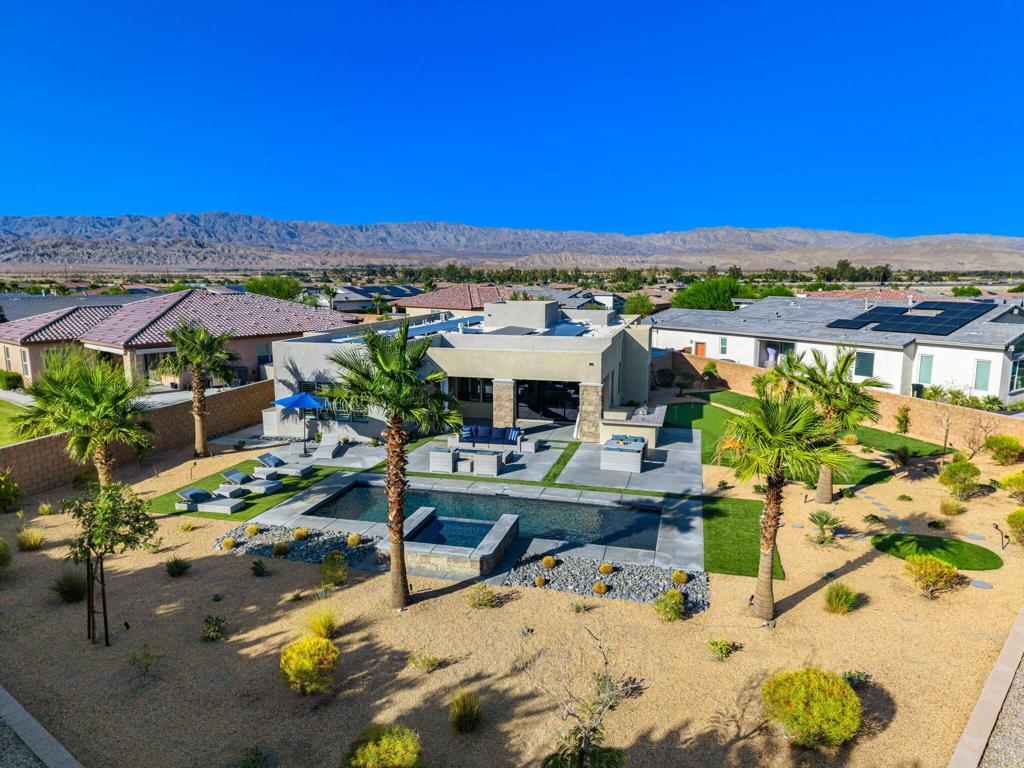 Tesla Collection Plan 3 residence (2018) is distinguished by its contemporary design and premier location on the largest available lot, encompassing 17,424 square feet resort outdoor living . This home features 3 BEDROOMS + DEN/ OFFICE/ 4TH BEDROOM, 3 BATHROOMS and OWNED SOLAR: exceptional property that provides expansive environment for outdoor enjoyment.The home offers a resort-style backyard meticulously designed for outdoor living and entertaining. The exterior amenities include a swimming pool, a spa enhanced with a cascading water feature, an outdoor BBQ area, a bricked gas fireplace, a unique over-water golf hole, a two-tier putting green, a bocce ball court, and a dedicated outdoor workout space . A covered balcony equipped with a grill, counters, and seating further enhances the outdoor experience.The interior of the residence showcases numerous upgrades, such as elegant glass cabinetry and doors, sophisticated recessed ceilings and lighting, soffits, exterior sliders, under-lit floating cabinets, a fireplace, integrated ceiling speakers, ceramic tile flooring, and plantation shutters throughout. The entryway features stunning high ceilings, complemented by 10-foot ceilings throughout the remainder of the home. The open living area is designed with sliding glass doors that create a seamless transition to the outdoor living space. The property also includes a finished, air-conditioned garage with an epoxy floor and built-in shelving. Furthermore, the home has 37 OWNED invisible SOLAR PANELS and features a modern flat roof design.Conveniently situated within the secured Genesis gated community, off Gerald Ford between Cook and Portola, residents benefit from swing arm and RFID tag-activated gates, two dog parks, an open play area, a community gym, pool, hot tub, and an outdoor grill and dining area. The community is managed by an active board and HOA that diligently upholds community standards.The location offers excellent access to I-10, key arterial roads, and is just 11 miles from Palm Springs airport. Additionally, the planned adjacent 27-acre Millennium Park and numerous amenities within 1.5 miles, including gyms, hotels, restaurants, a private High School, a former-PGA tour public golf course, and a minor league hockey arena, add to the desirability of this location. With 250 sun-filled days per year and an average daily temperature of 73.1 degrees, This Palm Desert location offers an ideal lifestyle.