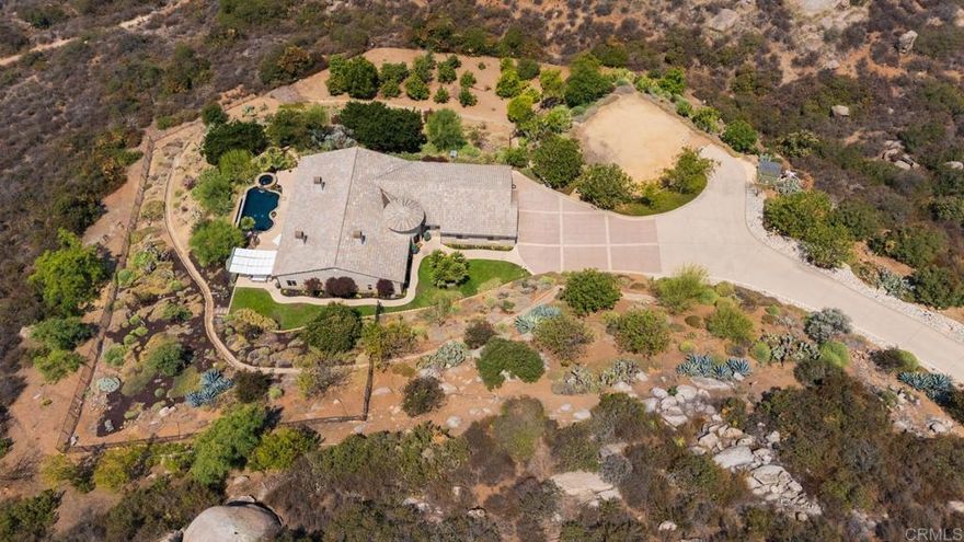 Occupying one of the highest ridge tops in the prestigious Talon’s Reach/Blossom Valley community, this 6-Acre, luxury estate offers unparalleled privacy, seclusion, and connection with nature. Situated at the end of Espinoza Road, a serene, rural-meets-refined corridor featuring gracious estates set on expansive acreage— this amazing property delivers both privacy and spectacular views. Set behind its own private gate at the end of a sweeping cobbled driveway, this absolutely gorgeous custom-built single-level home includes a pre-graded 3000 square foot building pad, perfect for an ADU, RV garage or guest house. Complete with a sizable citrus and avocado grove, this property offers plenty of space for the avid gardener.  Designed with modern elegance and natural beauty in mind, this unique estate blends sleek finishes, panoramic mountain-to-city views, and oasis-like serenity into one extraordinary property.  The open layout is filled with natural light, with expansive windows that capture sweeping vistas from nearly every room—bringing the outdoors in. Multiple living areas offer space for both grand entertaining and intimate gatherings, while an enormous chef’s kitchen anchors the home with high-end finishes, generous counter space, and seamless flow for culinary creativity. Designer upgrades and meticulous craftsmanship are found throughout, showcasing an attention to detail that defines luxury living. Step outside to an entertainer’s paradise: a zero-edge pool that seems to spill into the horizon, with golden sunsets and starry skies as your nightly backdrop. Just imagine soaking in your custom spa nestled among palo verde trees on a moon-lit night. Or, dining under the stars beside the outdoor fireplace as you take in the spectacular mountain and city views.  This rare estate captures the essence of Blossom Valley—peaceful, private, and perfectly located. Whether you’re seeking a luxury residence, multi-generational living opportunity, or a nature-inspired sanctuary, this home delivers it all. With modern sophistication, natural beauty, and room to expand, it stands out as one of the most desirable properties in East County!