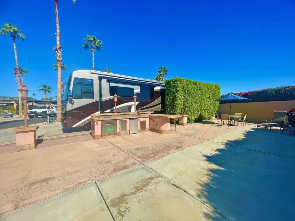 This furnished and well-maintained perimeter lot at Outdoor Resort Indio offers a perfect starter property for luxury RV enthusiasts, featuring a west-facing orientation with partial mountain views, privacy hedges, and close proximity to the pool. Equipped with an outdoor kitchen that includes an oven, cooktop, BBQ, double sink, fridge, and ample storage, the lot also boasts two dining tables with seating for four, two sun tanning beds, a large umbrella, and a bar with two high bar chairs--ideal for relaxing or entertaining. As an ORI owner, you'll enjoy access to the resort's extensive amenities and activities, making this property an exceptional blend of comfort and opportunity.‍