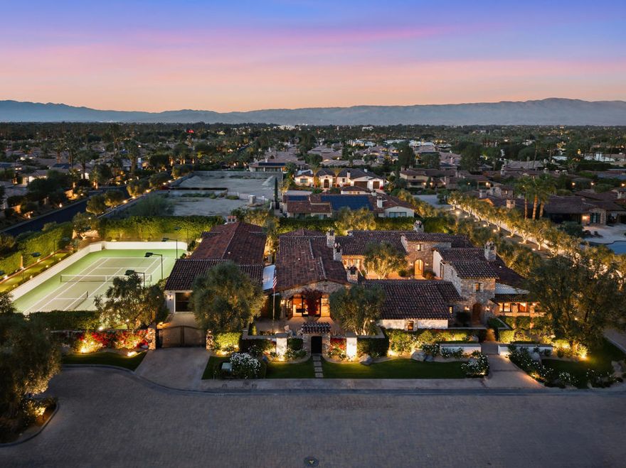 Experience luxurious desert living in an iconic private compound double-gated within the exclusive enclave of Bella Clancy. Designed for those who value architecture, privacy, quality and effortless indoor-outdoor living, this 6,275sf residence delivers richly appointed living space along with an additional 1,200sf of covered outdoor living designed for entertaining, relaxation, and timeless elegance. The interiors embrace classic warmth--arched lines, rich textures, and generous proportions. The great room flows effortlessly into the inviting chef's kitchen and formal dining area creating a welcoming atmosphere ideal for intimate gatherings or large celebrations. The main home has three spacious ensuite bedrooms plus an office with sitting area and powder bath, while the detached guest casita, complete with its own bar, sitting room, full bathroom and powder bath, offers the charm of a private bungalow. A one-of-a-kind fitness room and spa offers a personal sanctuary for rejuvenation and self-care. At the heart of the home lies an oversized central courtyard, reminiscent of old-world villas. A graceful water feature, warm string lighting, and a wood-or-gas-burning fireplace set a romantic tone for evenings under the desert sky. Surrounding living spaces open naturally to this courtyard, blending indoor and outdoor living. With 2 combined lots equally almost 1 acre of land, the estate's outdoor amenities create a private resort experience. The covered pavilion houses a bar complete with sink, dishwasher, storage, counter seating and TV, a game area with a pool table and a living room with a wood burning fireplace. A sunken dining area offers an unforgettable setting for dinners beneath the stars. The pool and spa with cascading waterfall deliver relaxation amid sweeping mountain views, while the five-hole putting green and bocce ball court add an element of classic leisure. For recreation on a grand scale, the property features a freshly surfaced sunken, fully lit tennis court, also striped for two pickleball courts, allowing for day-to-night play in complete privacy. Luxurious, secluded and masterfully designed, 4 Via Lantico stands as one of Rancho Mirage's most remarkable estates--where Mediterranean character and desert serenity create an unmatched lifestyle.